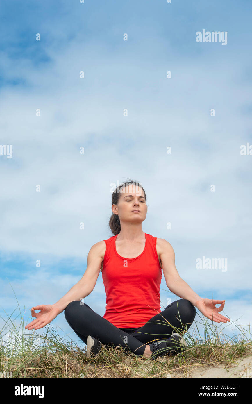 Donna seduta gambe incrociate e la meditazione, la pratica dello yoga al di fuori. Foto Stock