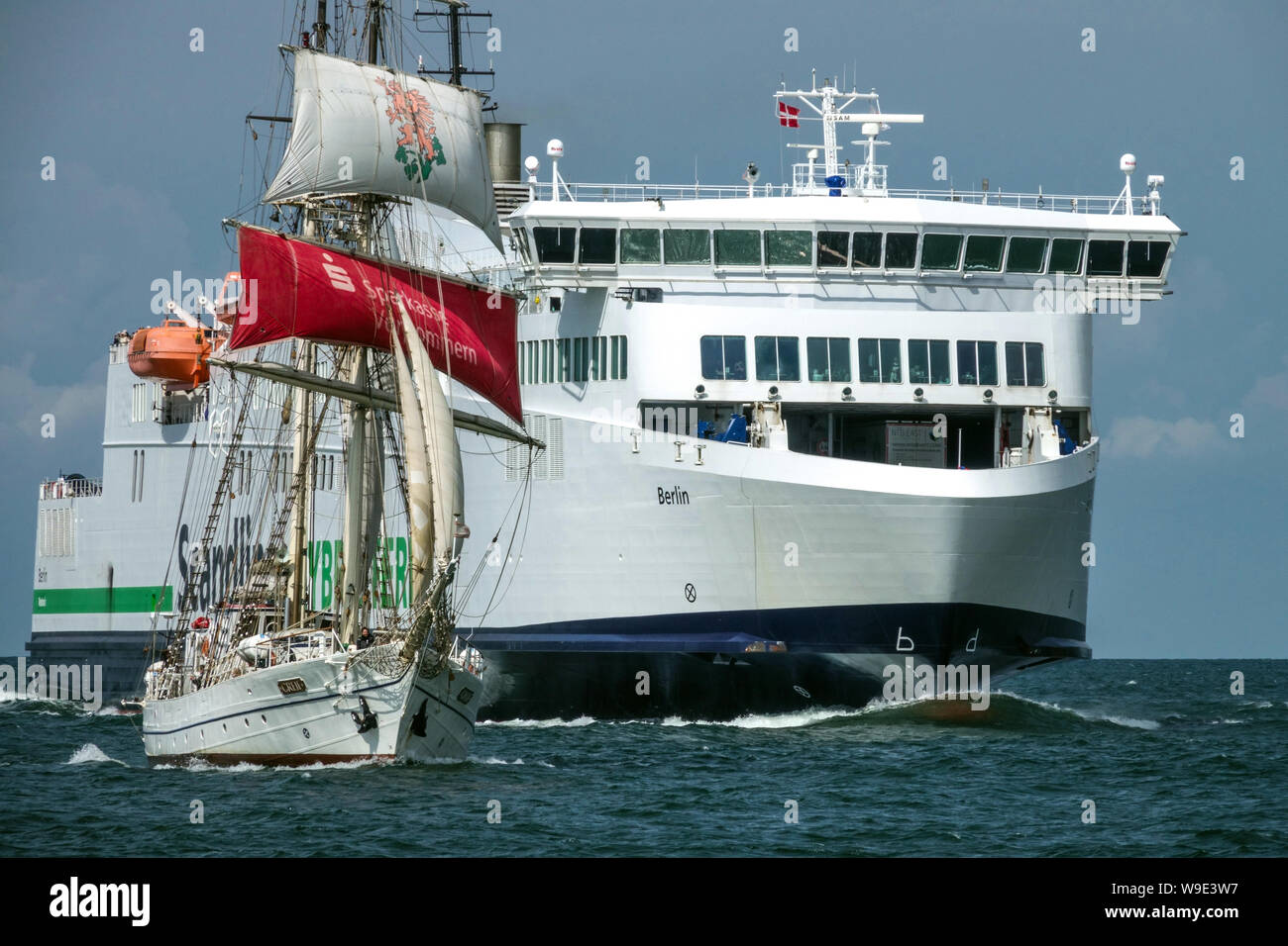Barca a vela e Scandlines traghetto ibrido in avvicinamento al porto, Rostock Germania Foto Stock