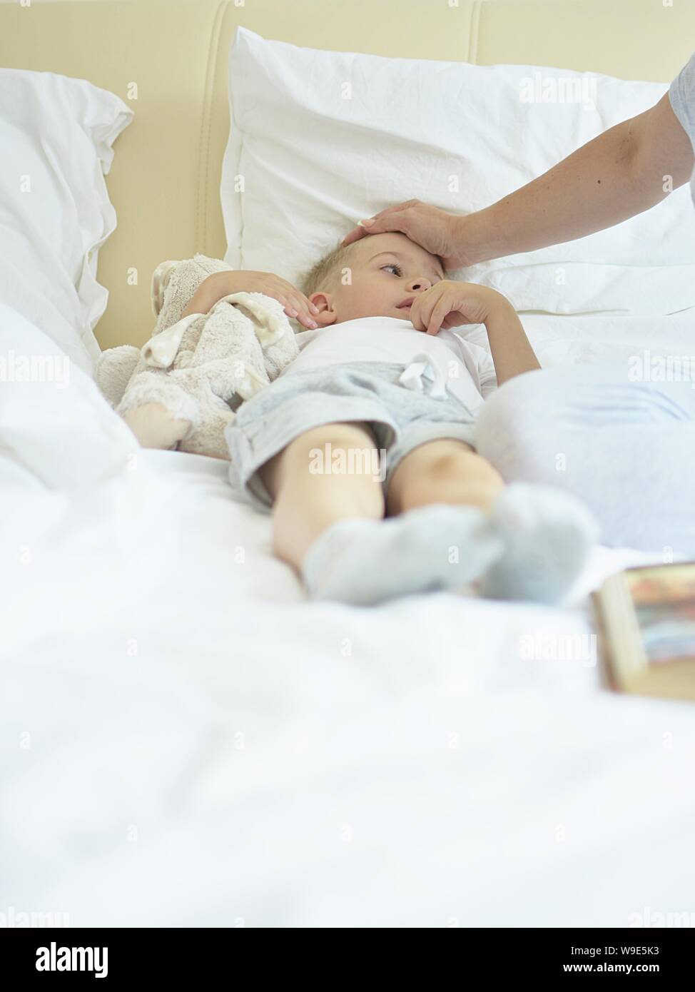 Bambino malato giacente in letto matrimoniale in camera da letto Foto Stock