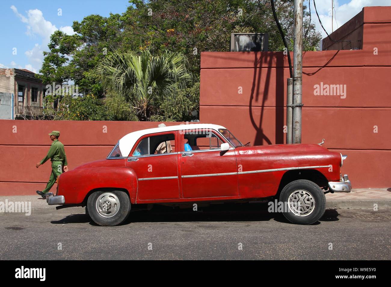 SANTIAGO DI CUBA - Febbraio 10, 2011: la gente a piedi dal classico americano "yank cisterna " auto in Santiago de Cuba. Cuba ha uno dei più bassi auto pro-capite rat Foto Stock