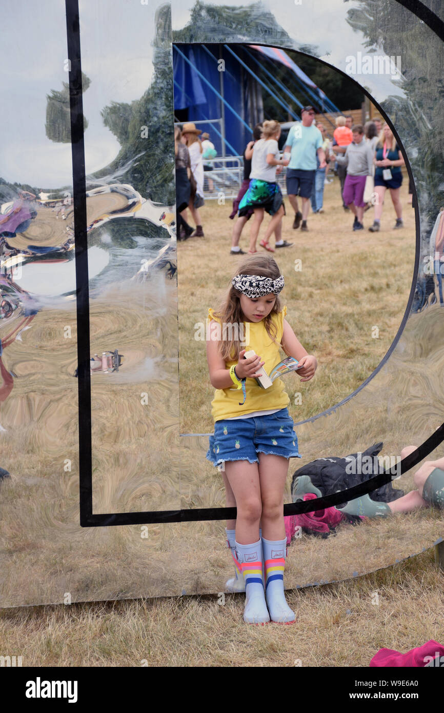 Latitude Festival, Henham Park, Suffolk, Regno Unito Luglio 2019. Ragazza la lettura di un libro su una delle lettere gigante Foto Stock