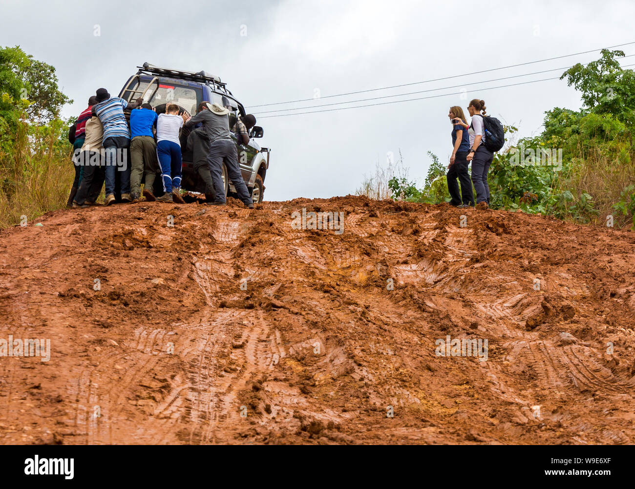 Gli studenti di un fieldtrip in Malawi spingere un veicolo a filamento di una strada fangosa Foto Stock
