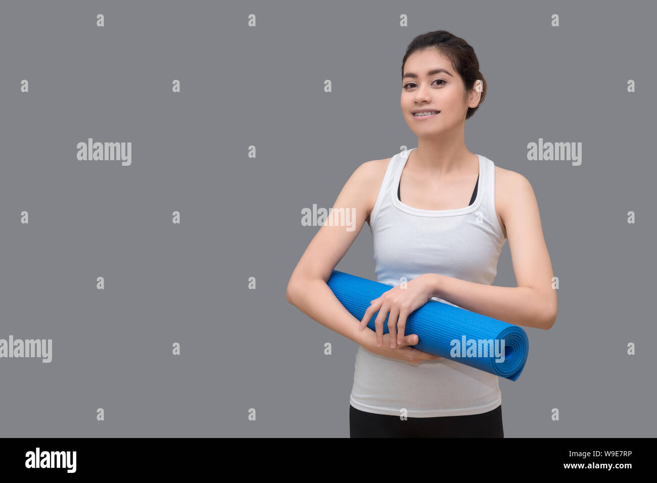 Giovane donna asiatica mentre tiene il suo materassino yoga al sano sport palestra. Lo yoga e la meditazione hanno buone prestazioni per la salute. Foto Stock