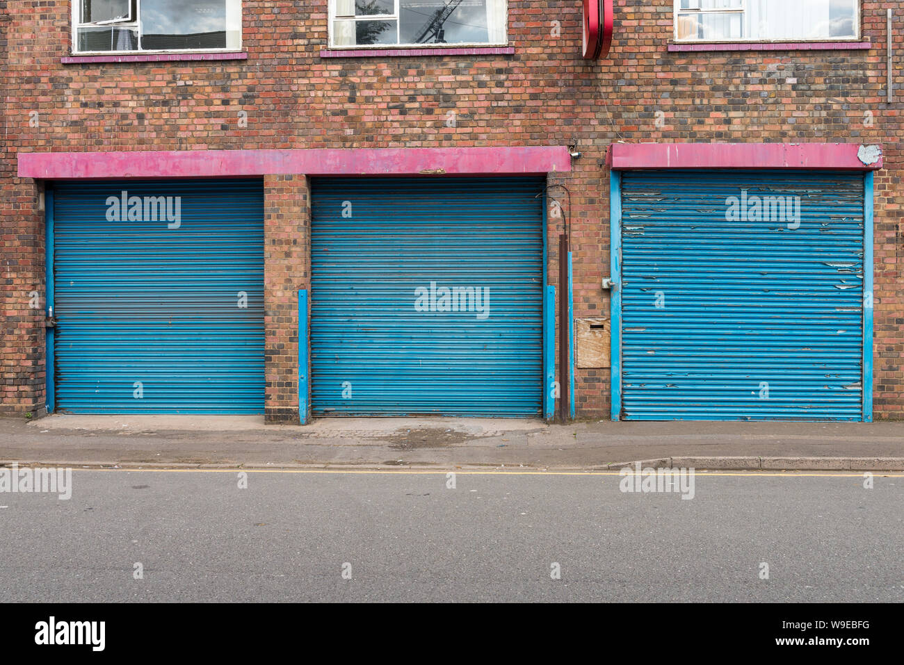 La riga tre dipinte di blu tapparella porte in Birmingham storico del quartiere di pistola in Aston, Birmingham Foto Stock