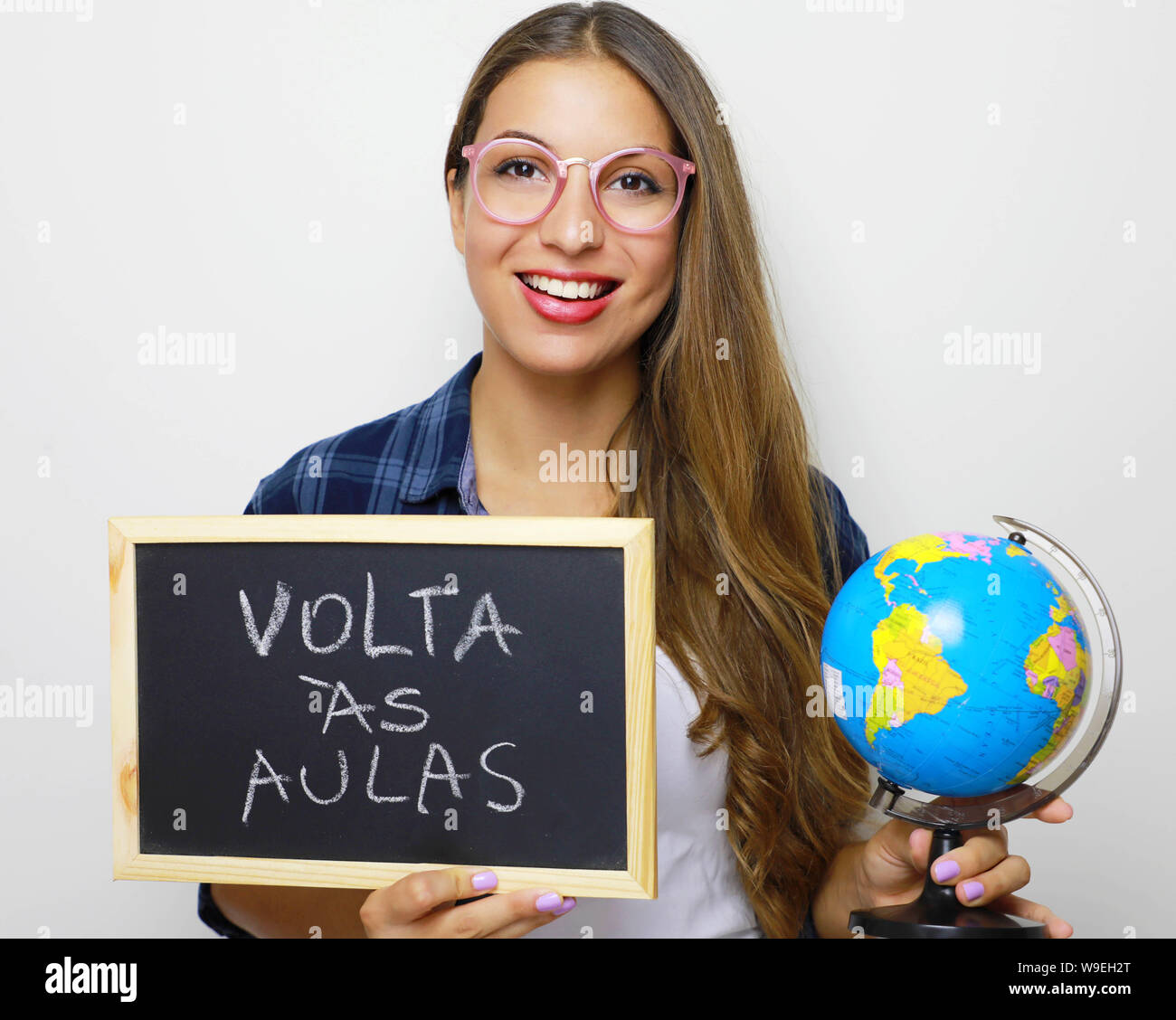 Il brasiliano giovane studentessa holding globe e blackboard portoghese con la scritta 'Volta come aule' (torna a scuola). Foto Stock