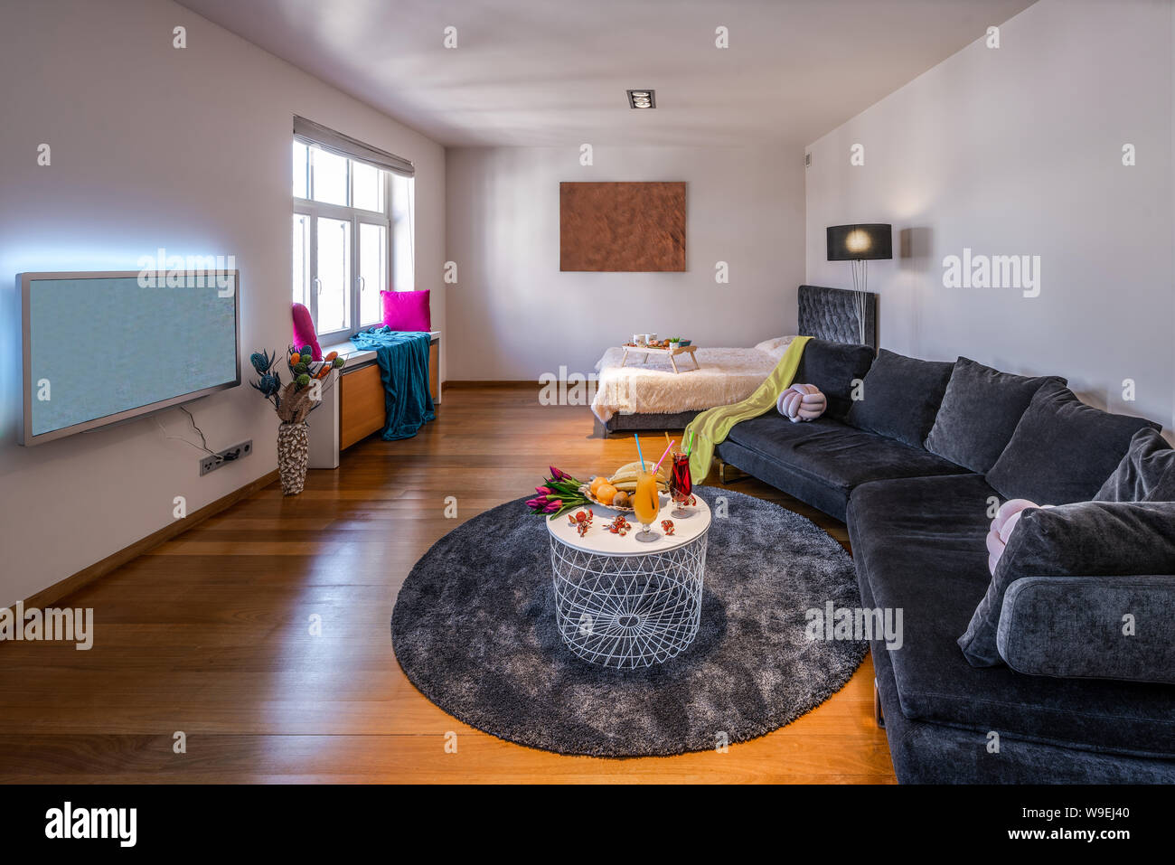 Divano grigio e coperto letto nel soggiorno. Tv sulla parete. Foto Stock