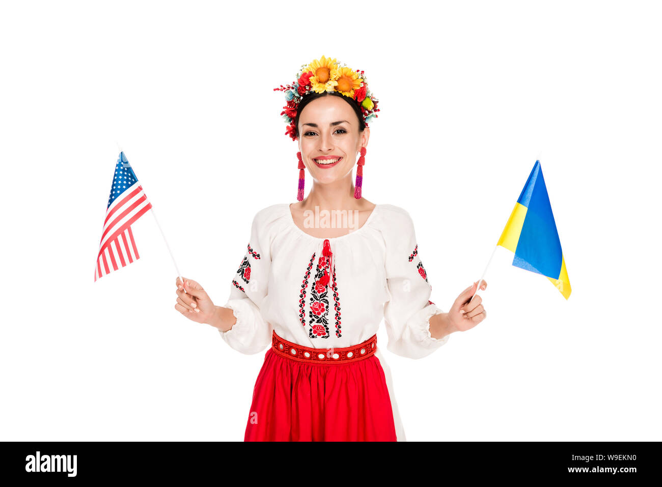 Sorridente bruna giovane donna in nazionale costume ucraino azienda americana e bandiere ucraine isolato su bianco Foto Stock