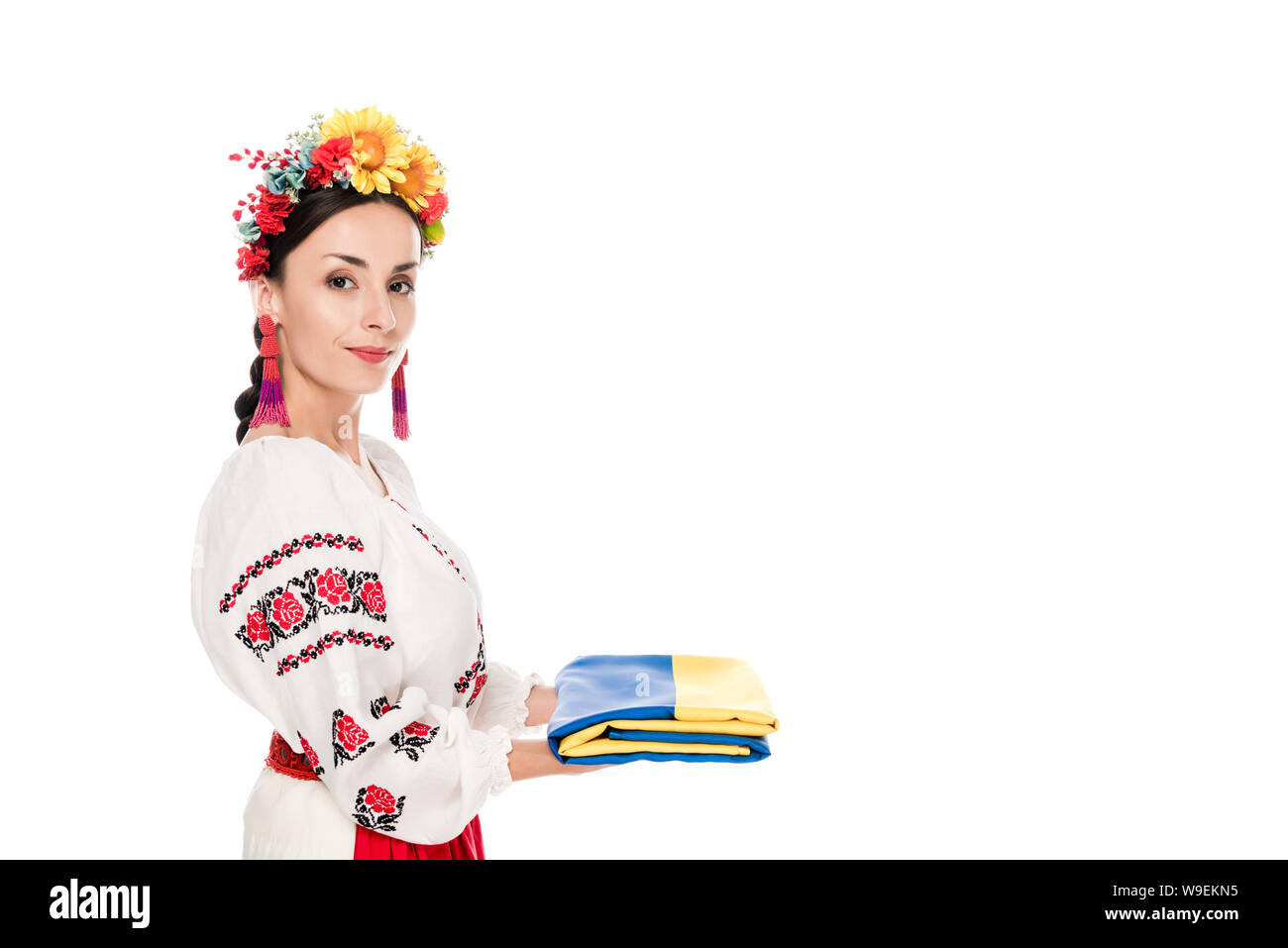 Vista laterale di bruna giovane donna in nazionale ucraino azienda costume bandiera isolato su bianco Foto Stock