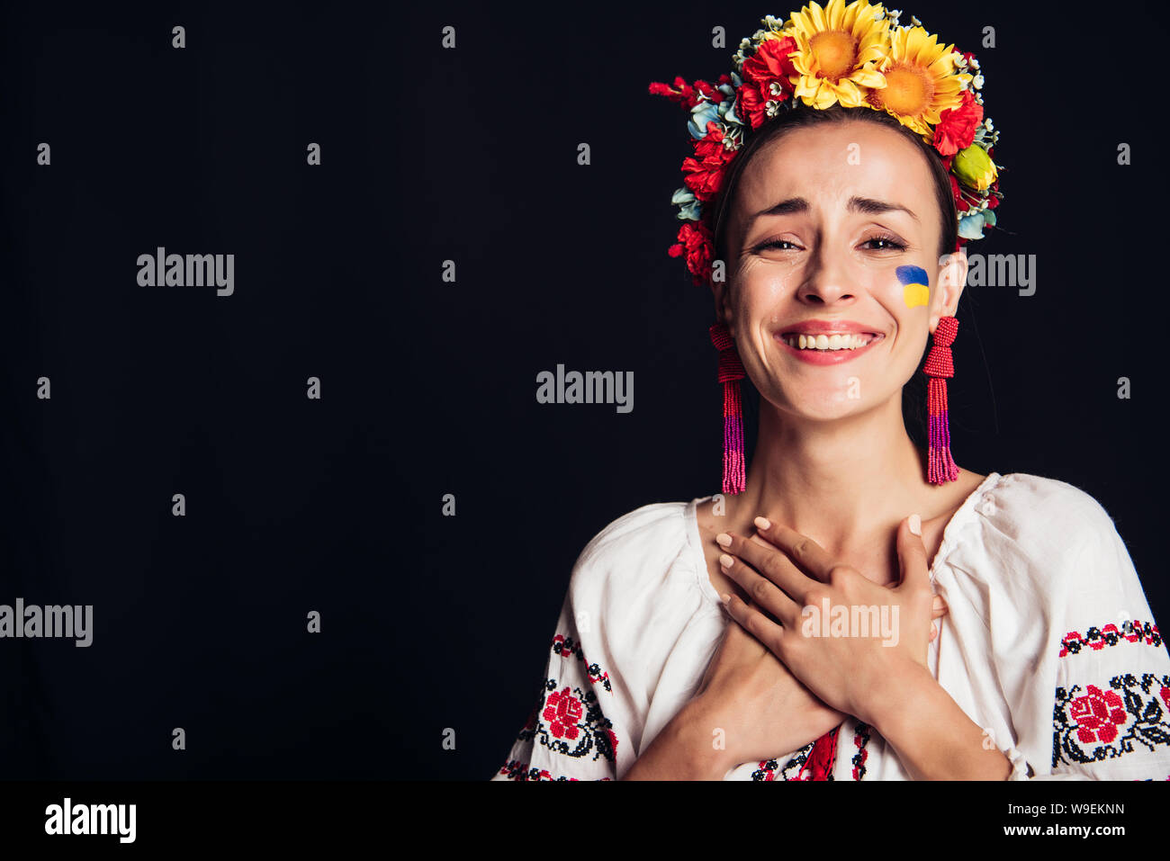 Felice bruna giovane donna in nazionale ucraino isolato in costume su nero Foto Stock