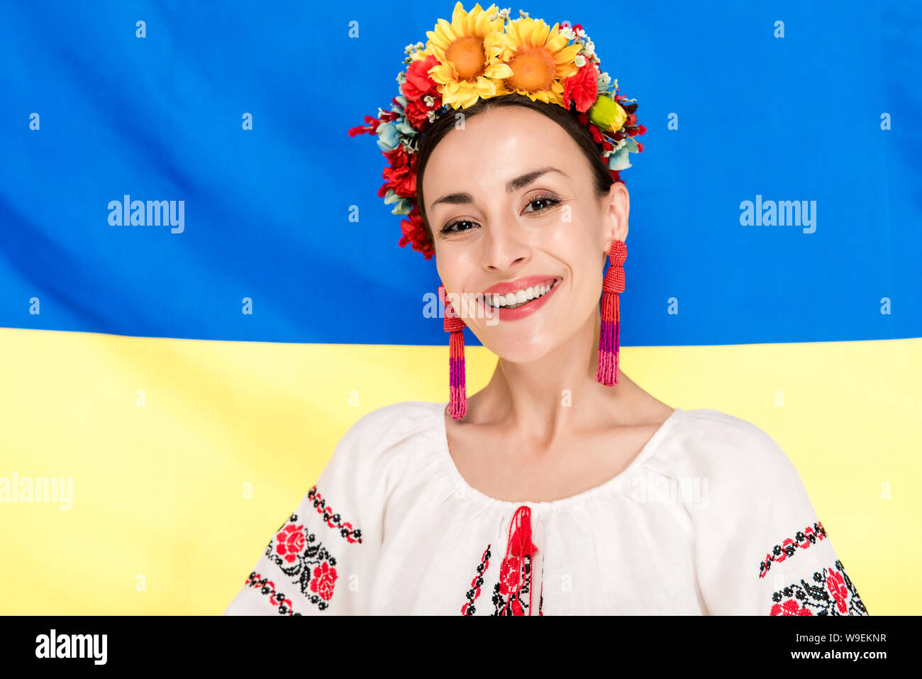 Felice bruna giovane donna in nazionali ucraine costume con bandiera di Ucraina sullo sfondo Foto Stock