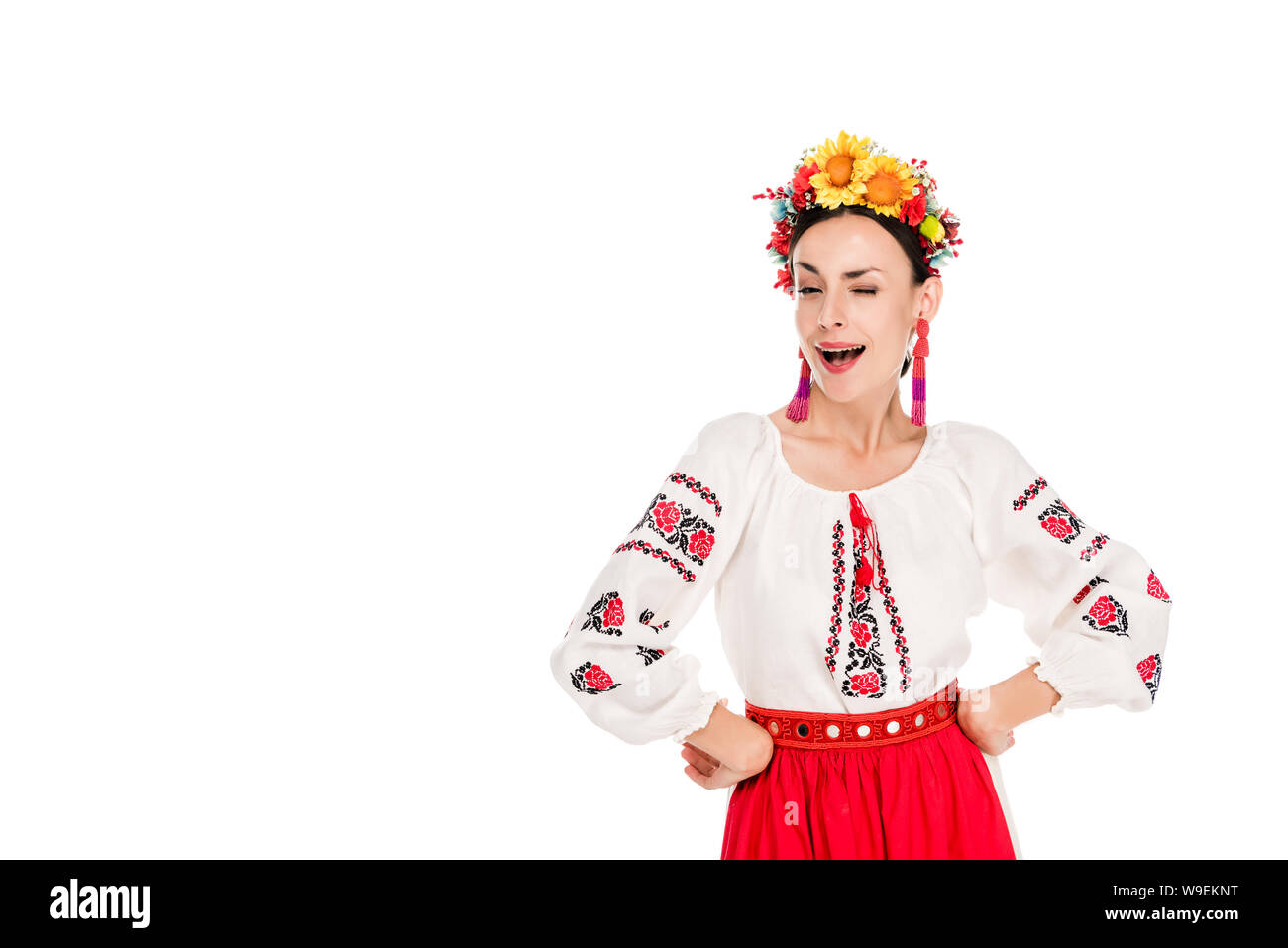 Bruna giovane donna in nazionali ucraine costume con le mani sui fianchi winking isolato su bianco Foto Stock
