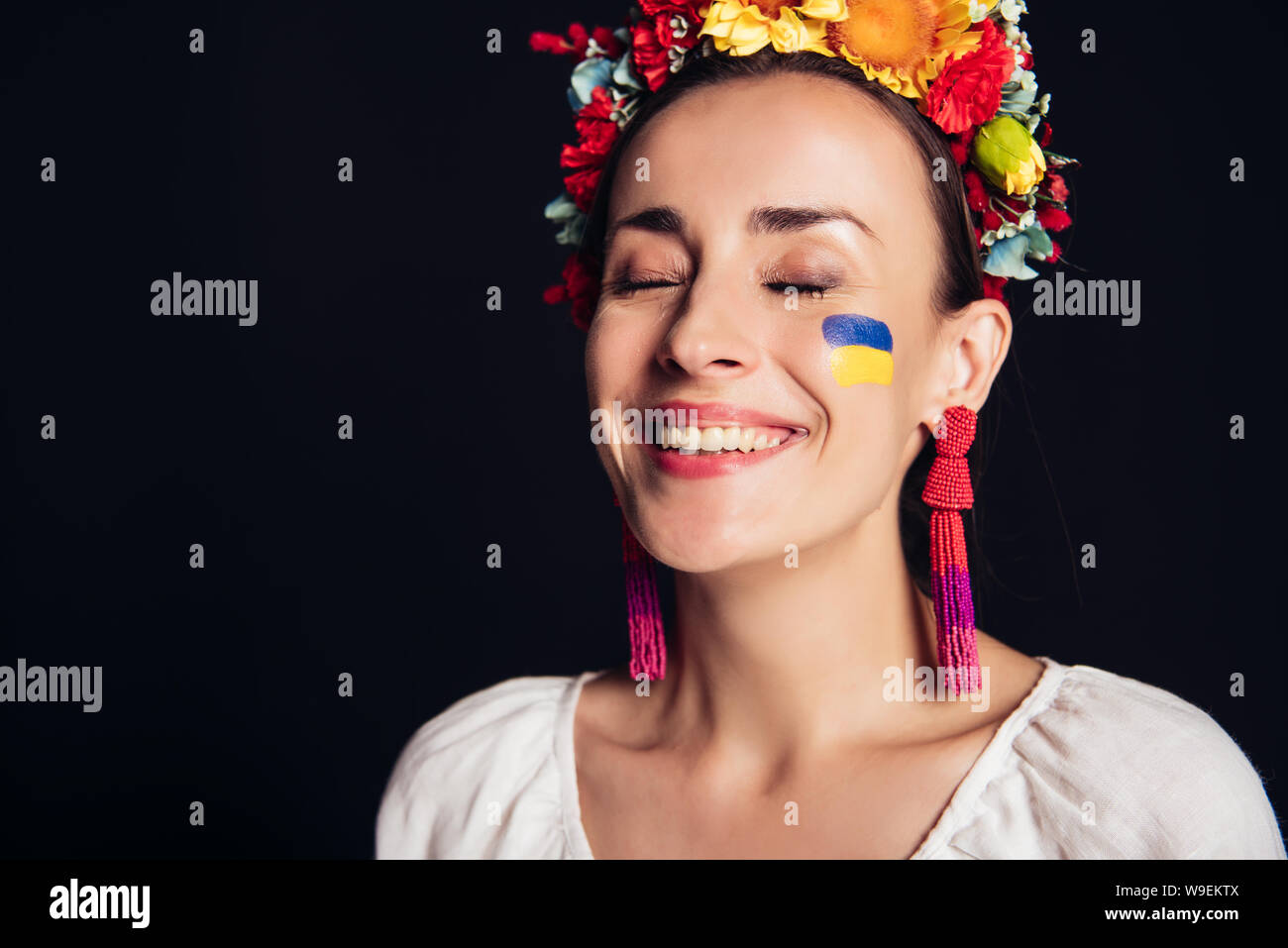 Felice bruna giovane donna in nazionali ucraine costume con gli occhi chiusi isolato su nero Foto Stock