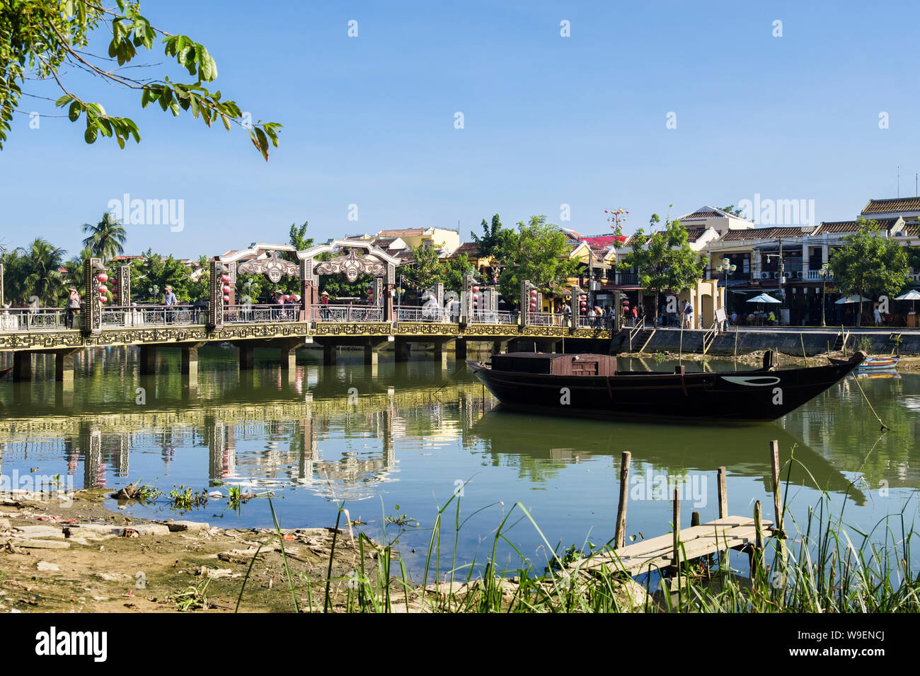 Scena di fiume con persone attraversando il vecchio ponte pedonale attraverso Thu Bon River nel quartiere vecchio di Hoi An, Quảng Nam Provincia, Vietnam Asia Foto Stock