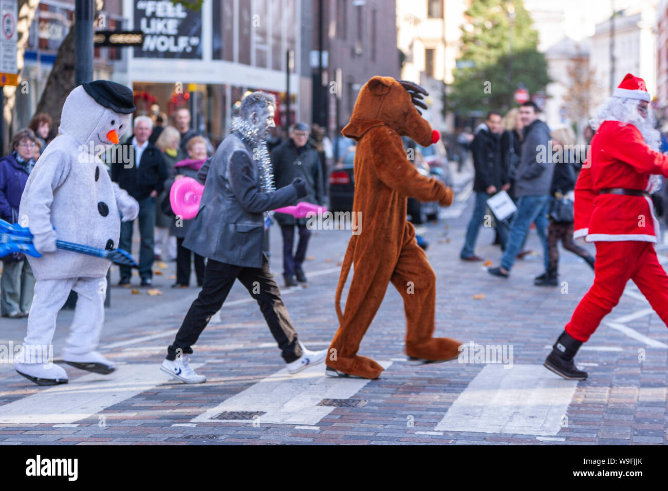 Gli uomini in abiti a fantasia attraversando le strisce pedonali, imitando Beatles, in London, England, Regno Unito Foto Stock