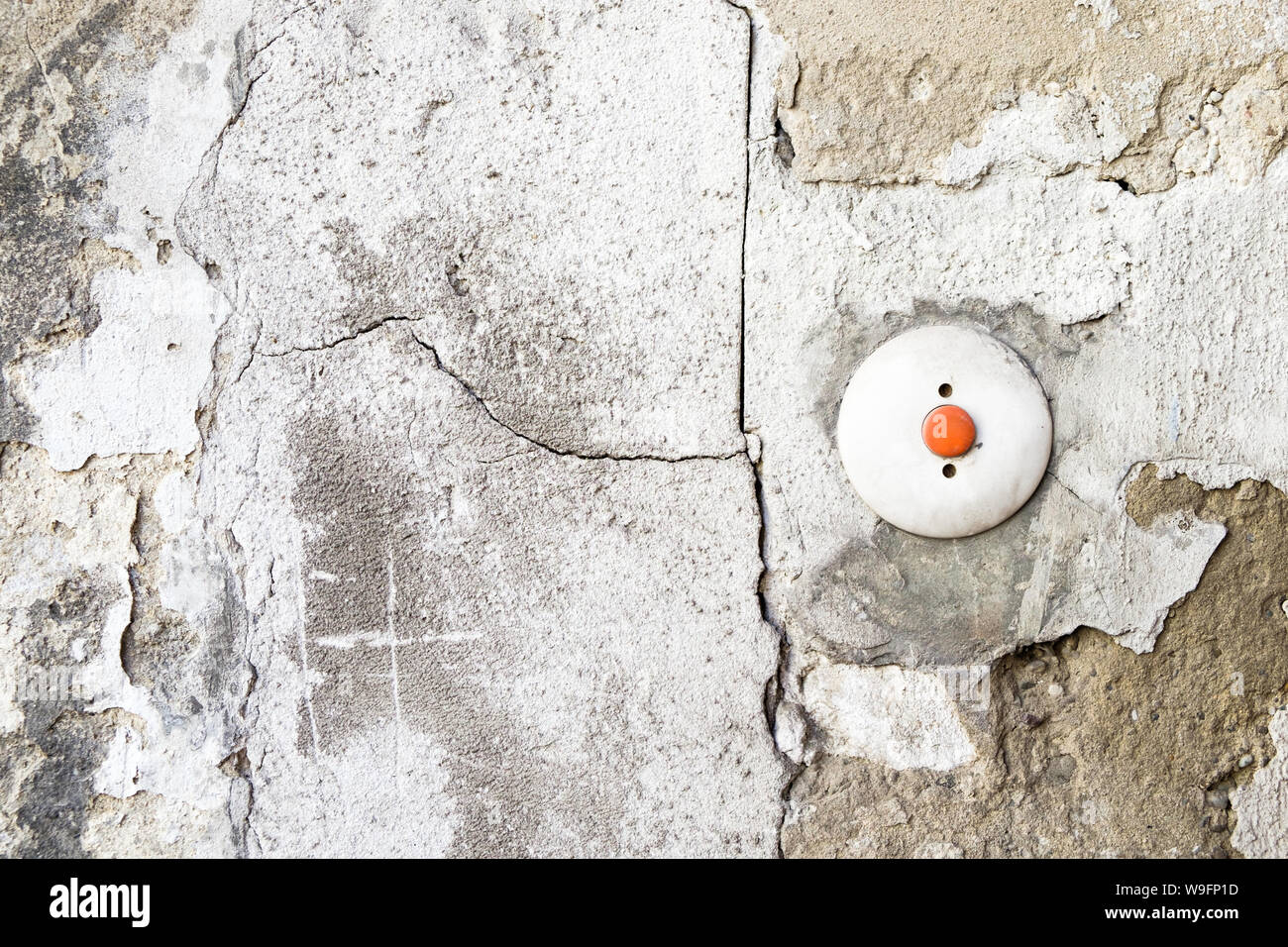 Un rosso e bianco del campanello su un incrinato, deterioramento della parete in calcestruzzo di Vienna in Austria. Foto Stock