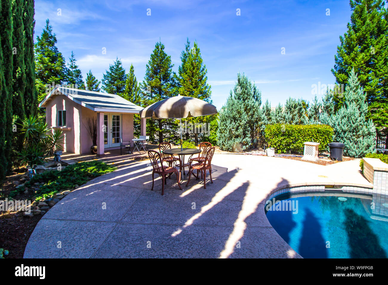 Pool House con tavolo e sedie e ombrellone accanto alla piscina Foto Stock