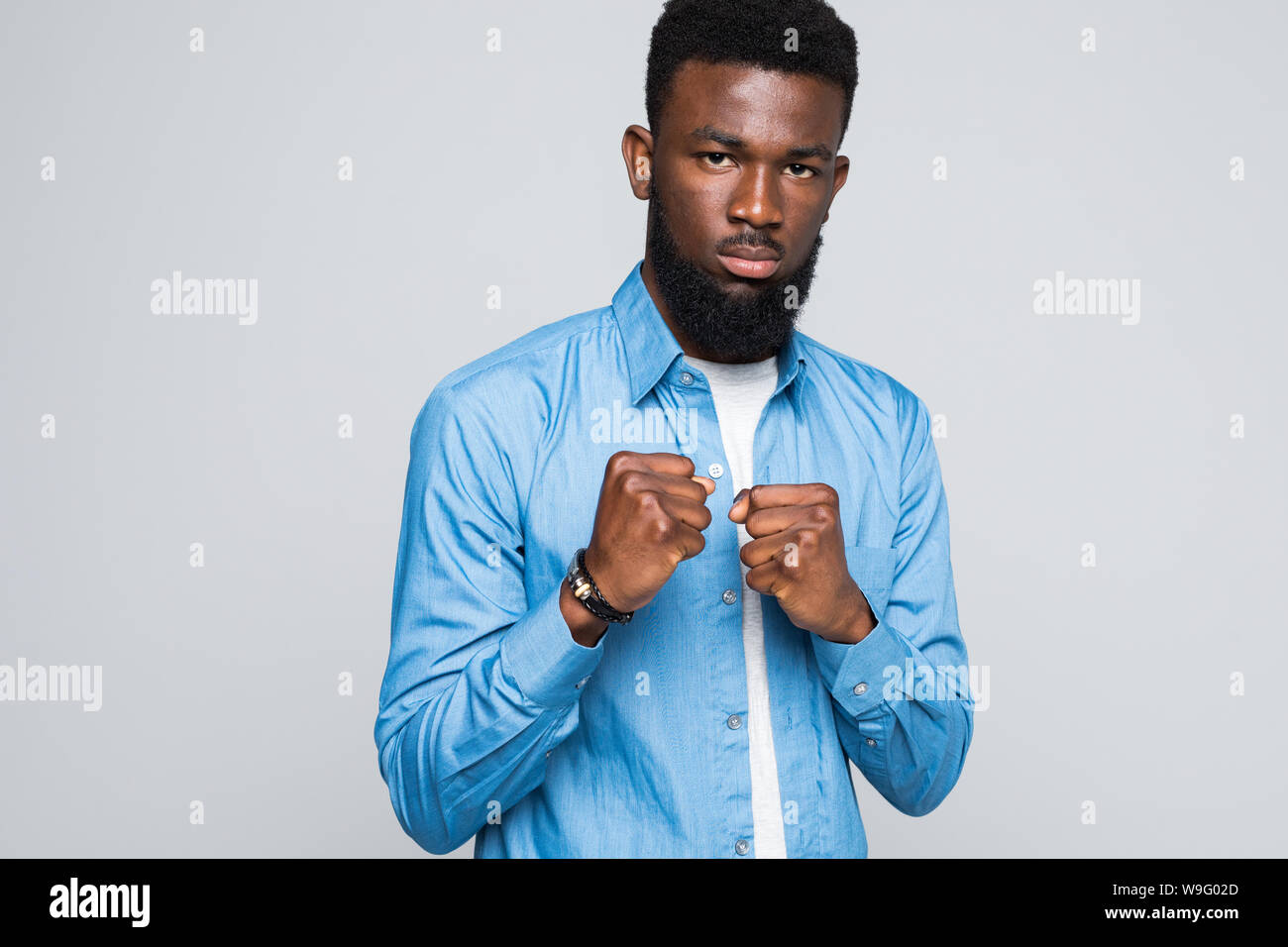 Arrabbiato americano africano uomo mostra pugno chiuso. Insoddisfatto di mad nero maschio giovane cliente dimostrando la potenza, dando attenzione, isolato sul prigioniero di grigio Foto Stock