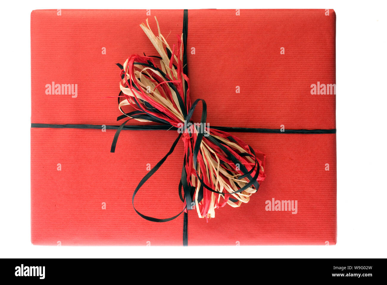 Un regalo in formato carta di colore rosso con una raffia bow isolato su uno sfondo bianco Foto Stock