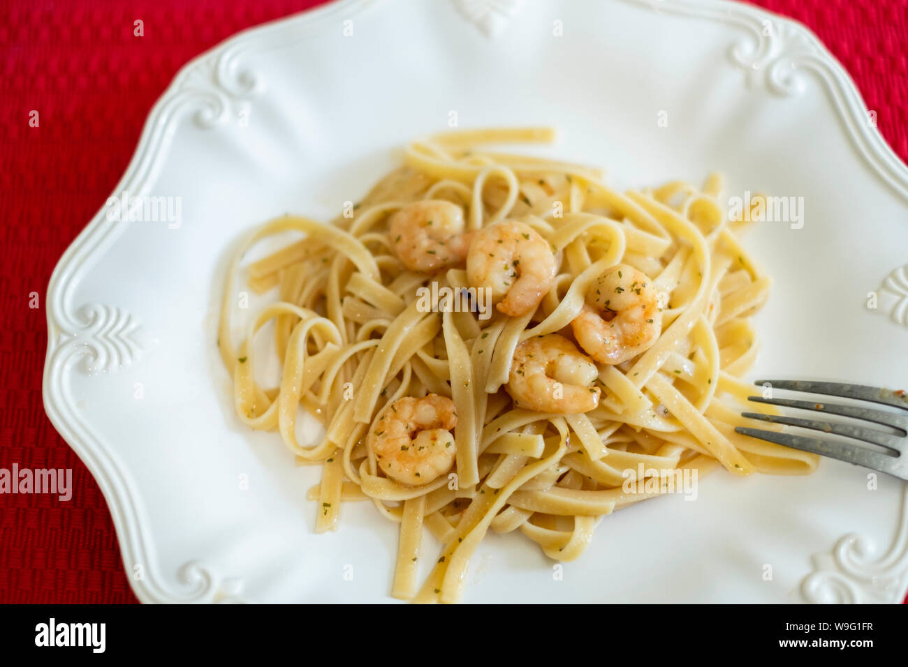 Scampi un aglio gamberetti conditi con il burro, servita su fettuccine. Piastra bianca, primo piano. Stati Uniti d'America. Foto Stock