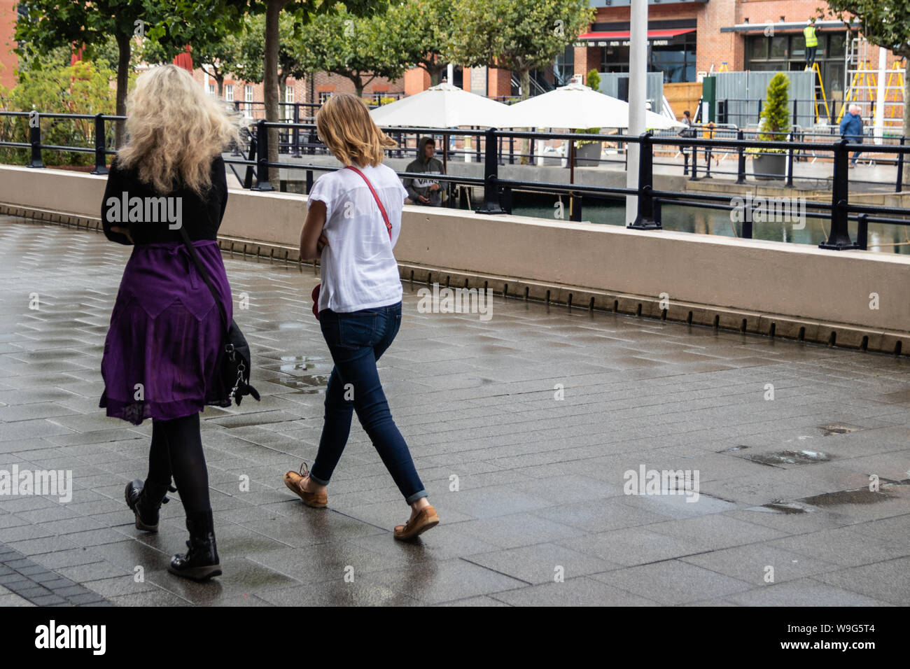Due donne in cammino insieme sotto la pioggia senza ombrelloni Foto Stock