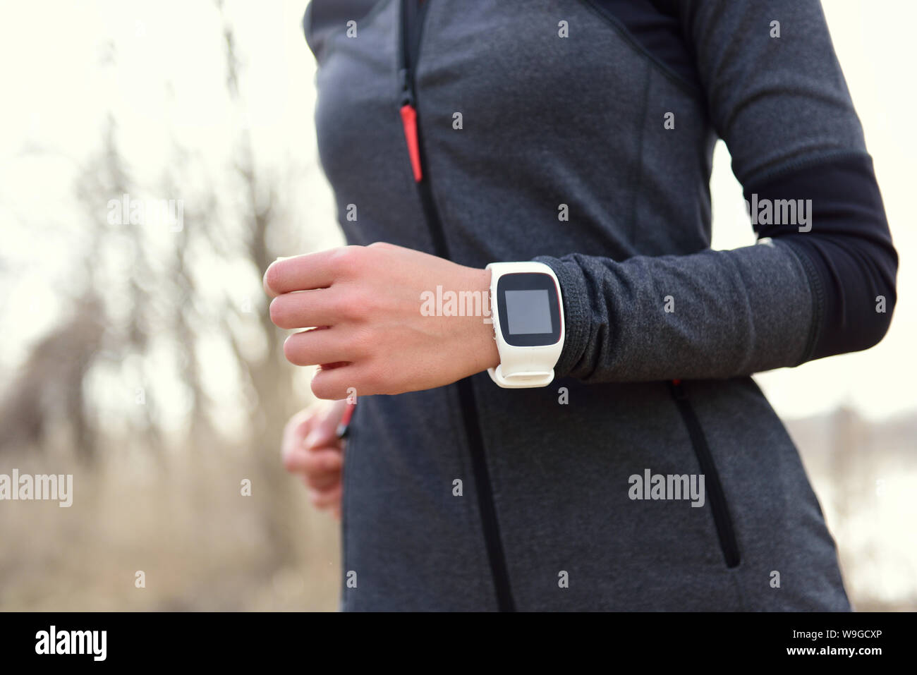 Smartwatch donna in esecuzione con monitor per la frequenza cardiaca. Vista dettagliata del polso femminile indossando smart sport guardare come il tracker di attività all'aperto durante l'allenamento cardio. Foto Stock