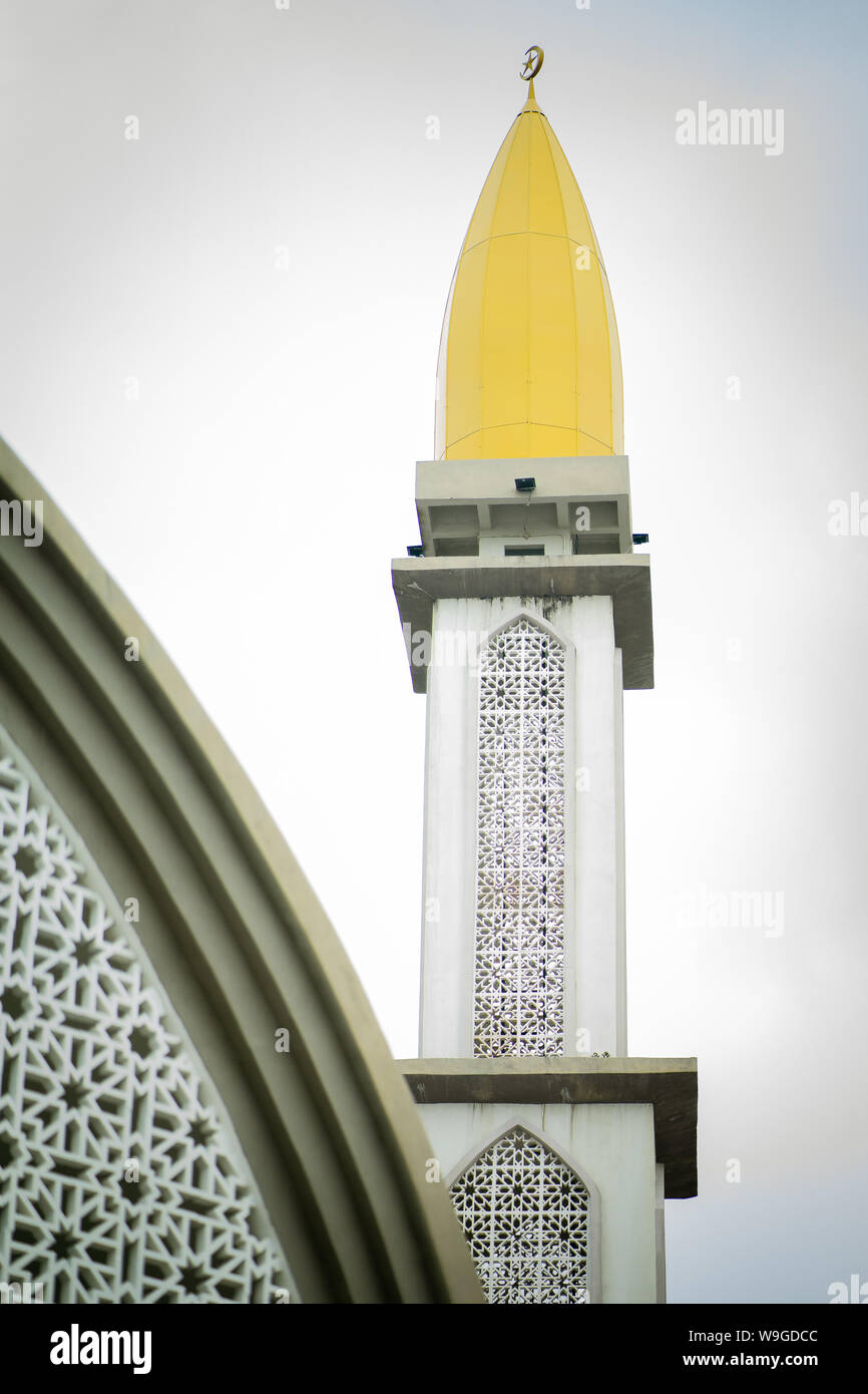 Un alto bianco e giallo minareto della moschea musulmana contro il cielo. Un minareto è un santuario islamico. Foto Stock