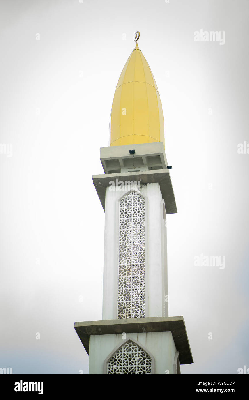 Un alto bianco e giallo minareto della moschea musulmana contro il cielo. Un minareto è un santuario islamico. Foto Stock