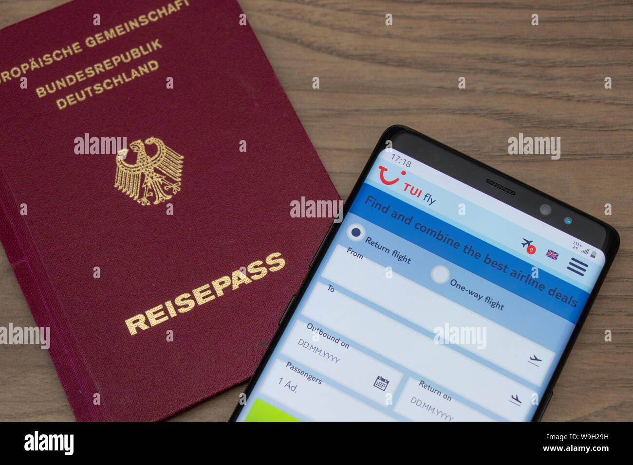 Passaporto tedesco e TUI fly sito web su uno smartphone visto mentre collocato su un tavolo di legno. Foto Stock