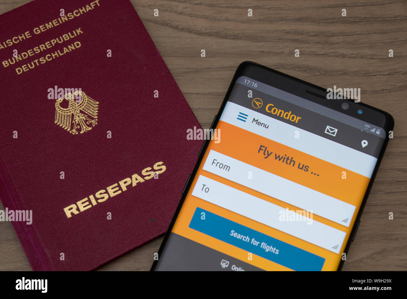 Passaporto tedesco e Condor Airlines sito web su uno smartphone visto mentre collocato su un tavolo di legno. Foto Stock