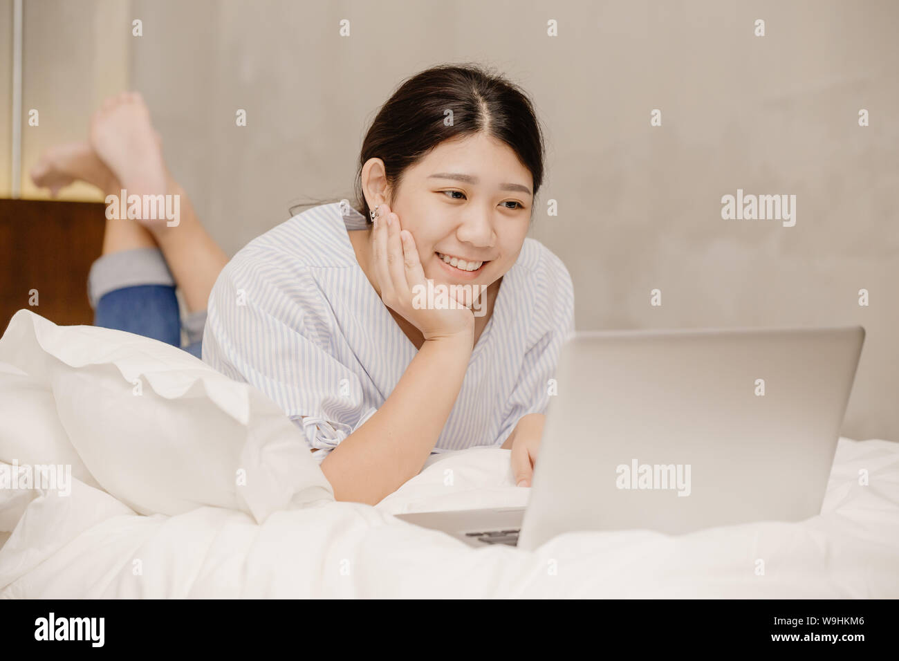 Lavoro felice Chubby girl teen lavora da casa utilizzando il computer portatile giaceva sul letto Foto Stock