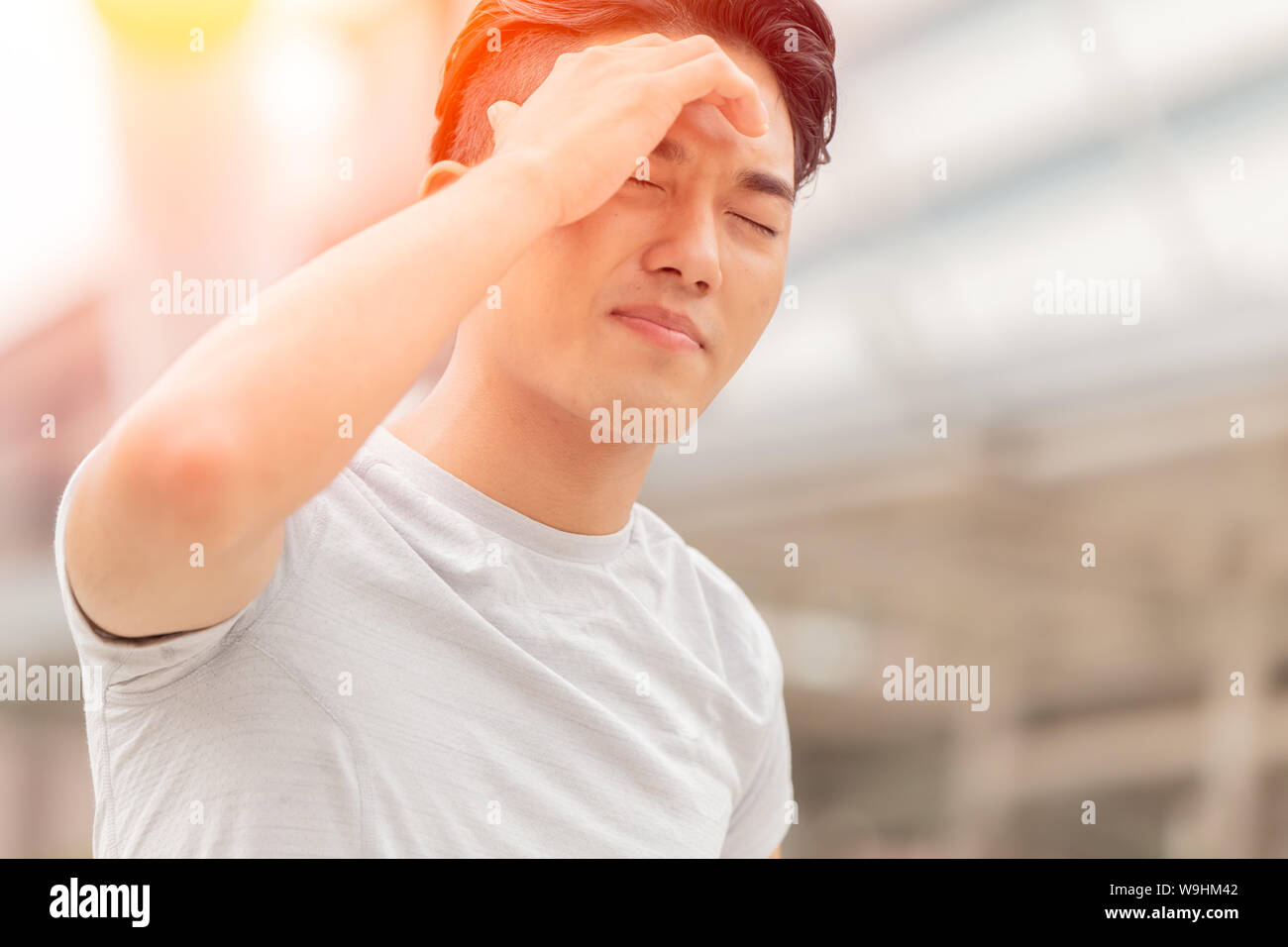 Teen maschio mal di testa da colpo di calore all'aperto estate calda forte giorno soleggiato Foto Stock
