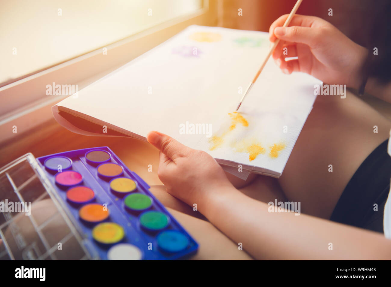 I bambini godono di mano pratica utilizzando un pennello per disegnare acqua verniciatura a colori per hobby a casa Foto Stock