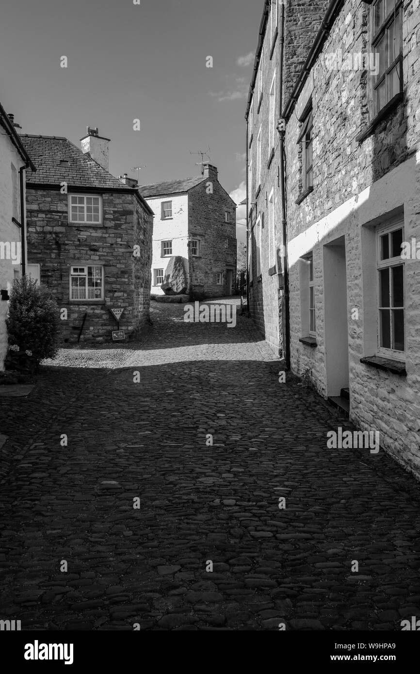 Una strada di ammaccatura, il piccolo villaggio di Dentdale, Cumbria, entro le Yorkshire Dales National Park Foto Stock