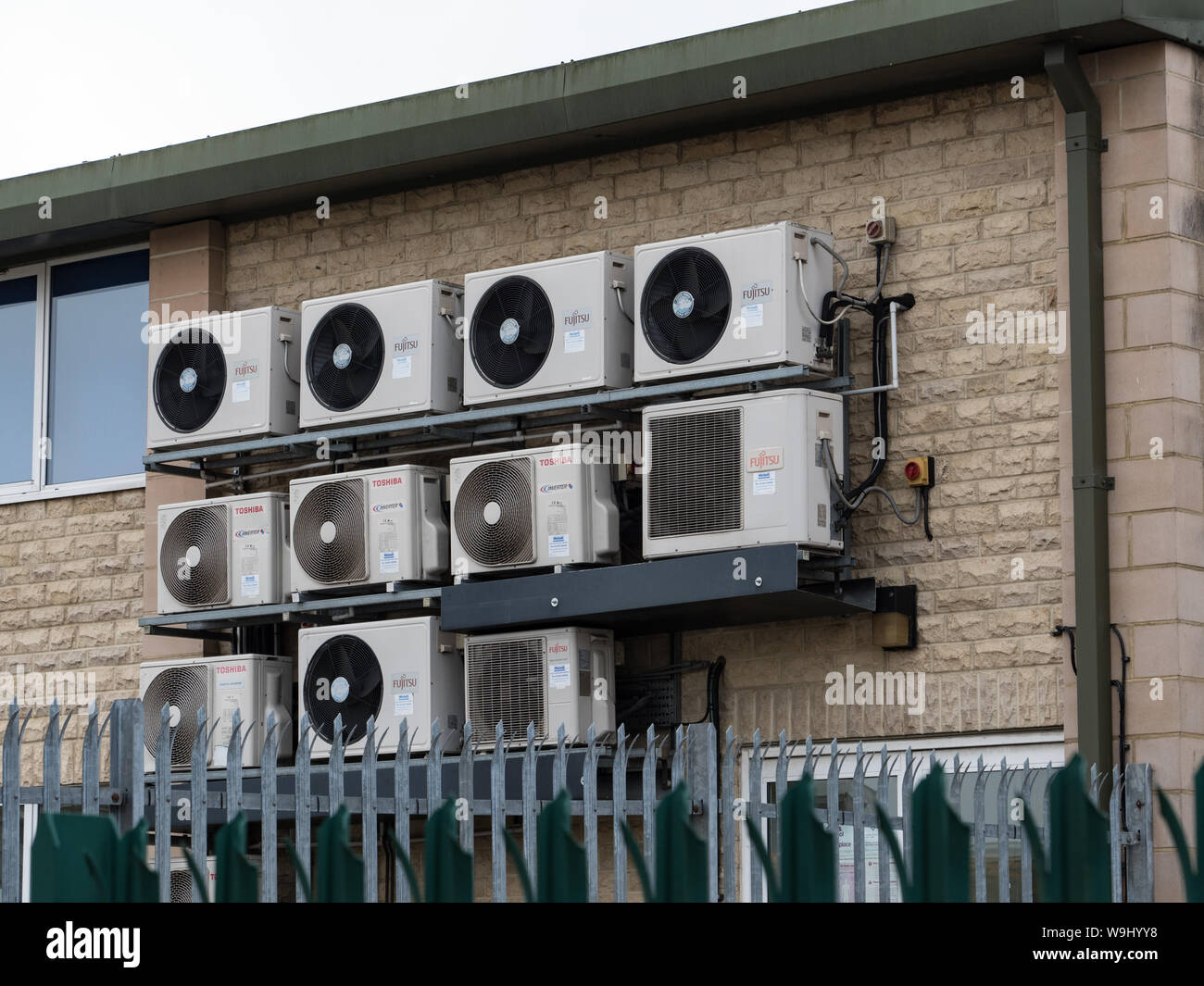 Una banca del condizionatore aria unità condensatore montato su una parete di fabbrica. England Regno Unito. Foto Stock