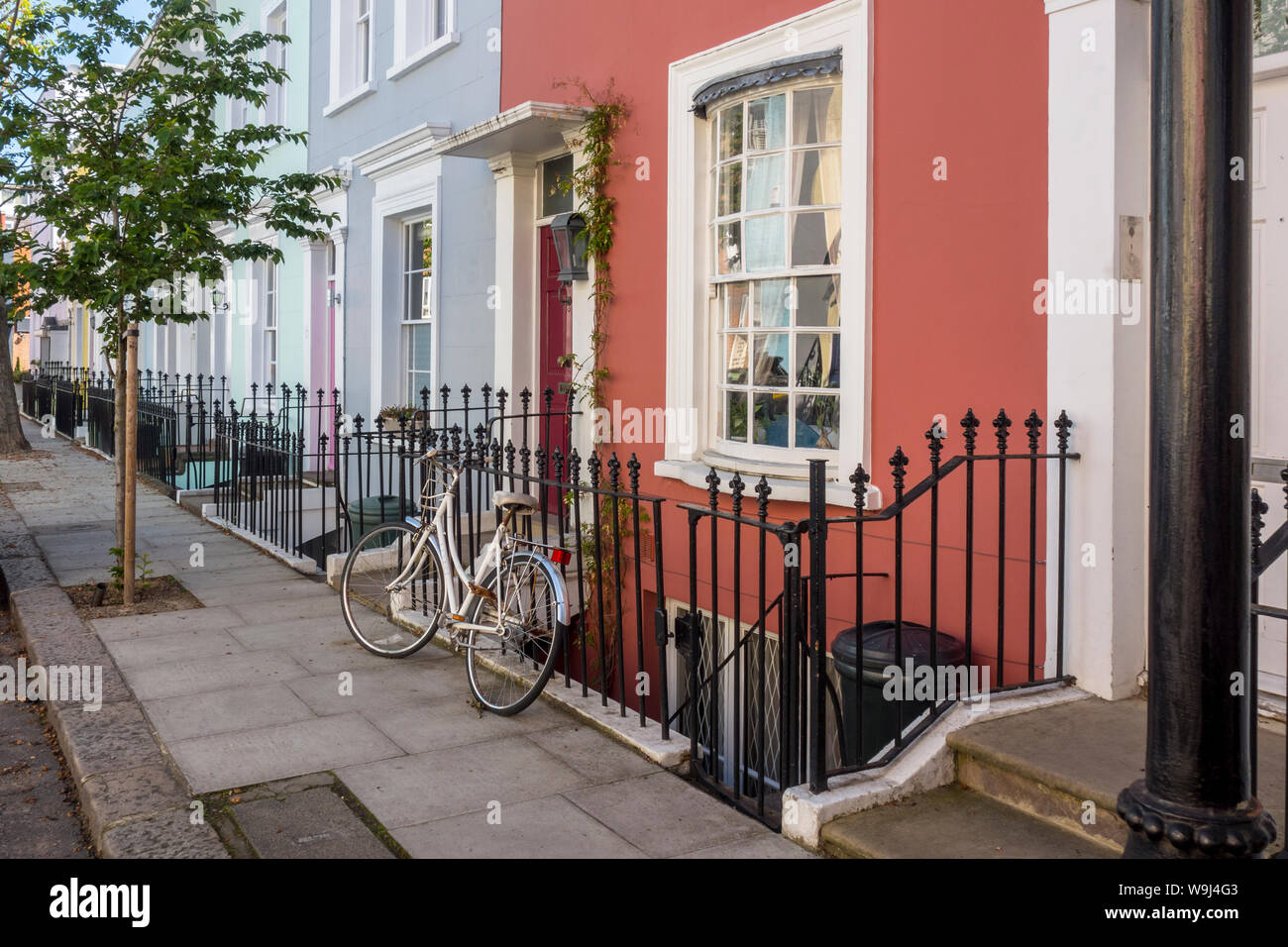 Bicicletta parcheggiata su ringhiere esterno colorato Notting Hill House, London, Regno Unito Foto Stock