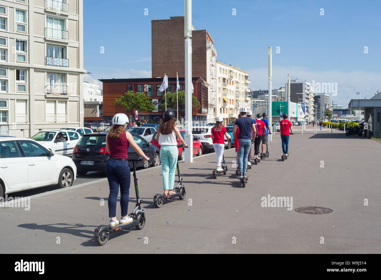 Un gruppo di giovani turisti sul lungomare di Le Havre, Normandia, Francia sull'e-scooter o scooter elettrici. Foto Stock