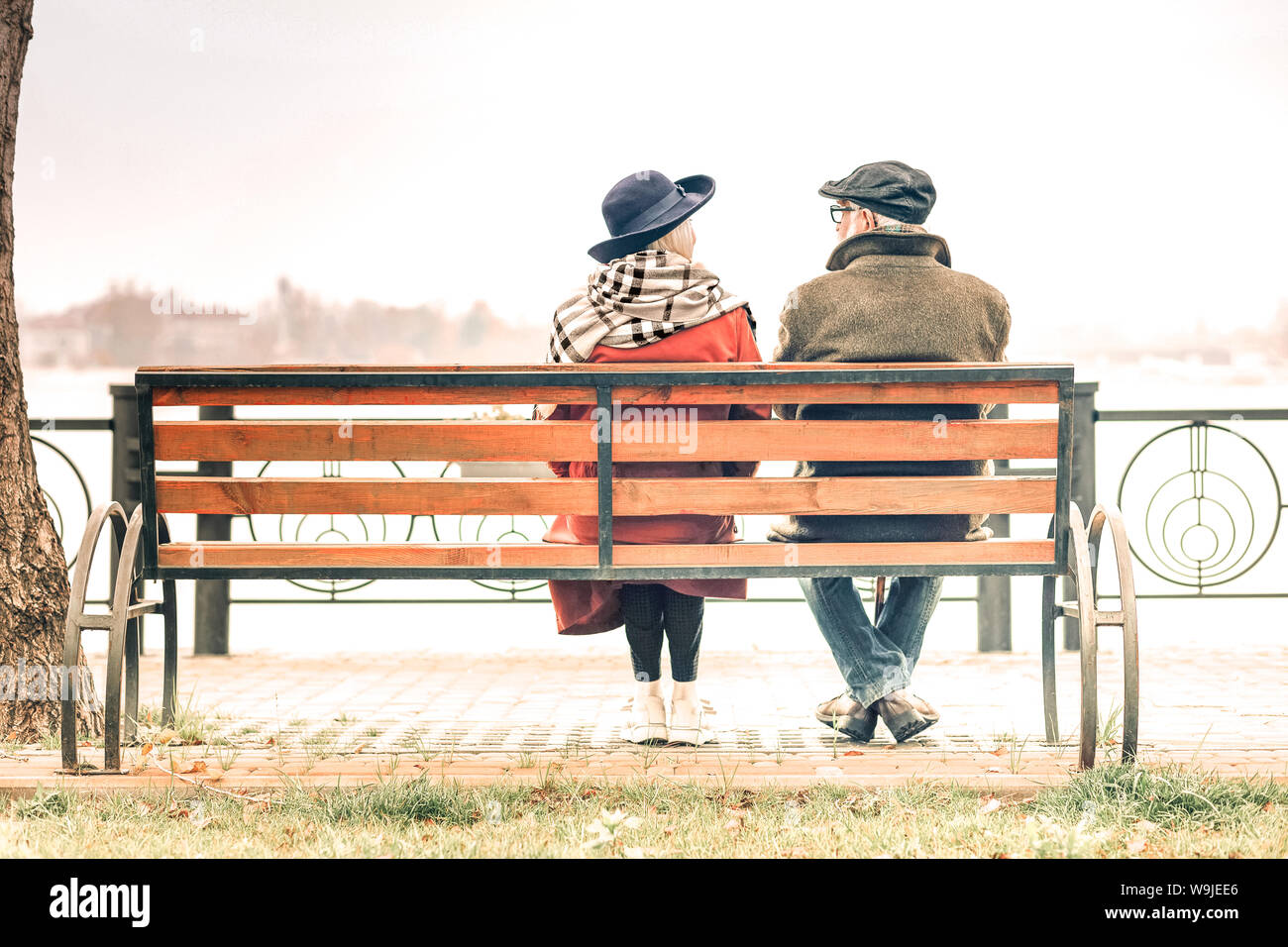 Vista posteriore di una coppia senior seduto sulla panchina nel parco autunnali Foto Stock