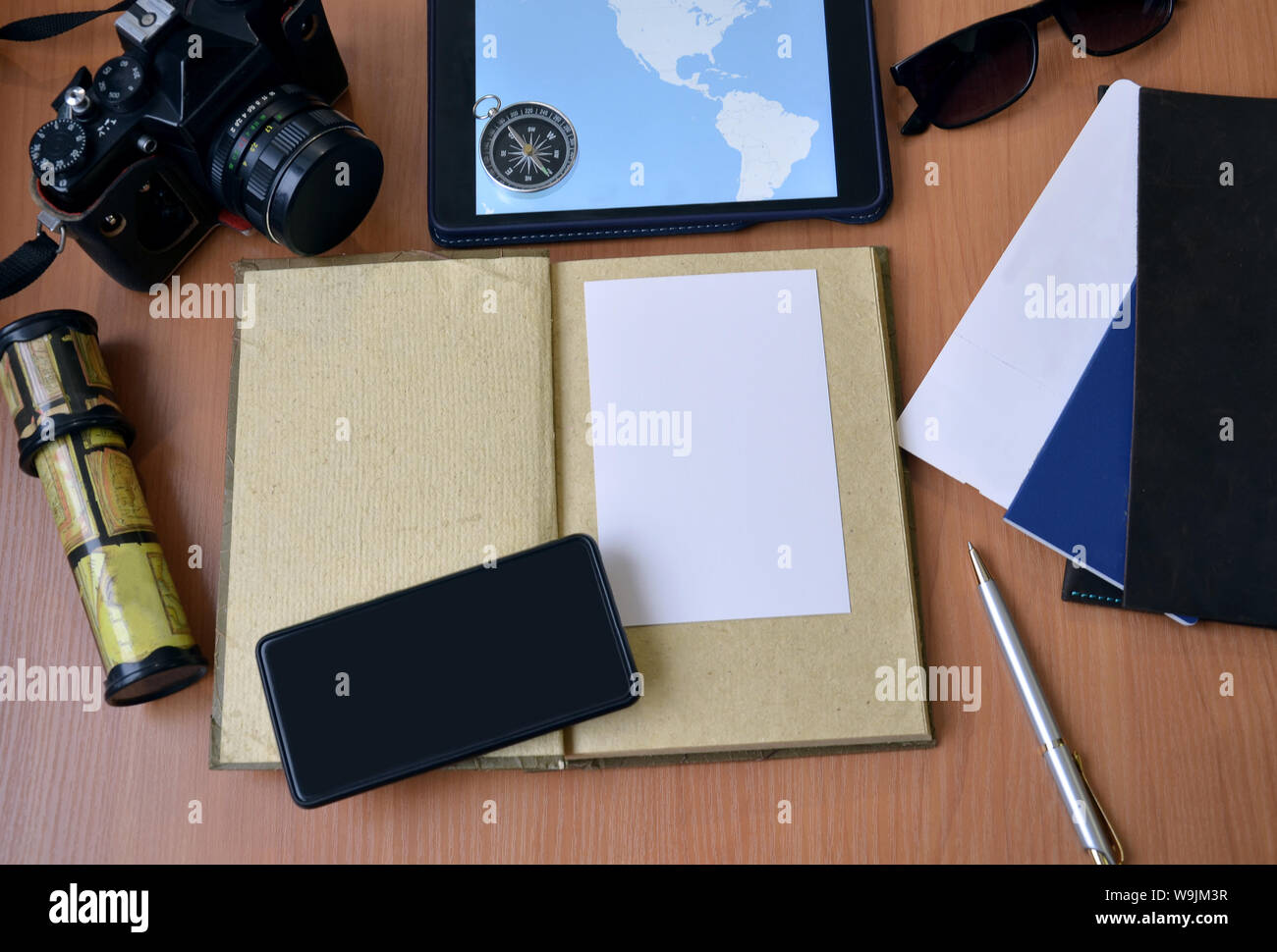 Notebook con penna, passaporto e biglietto, fotocamera, telefono e bussola su uno sfondo di legno Foto Stock