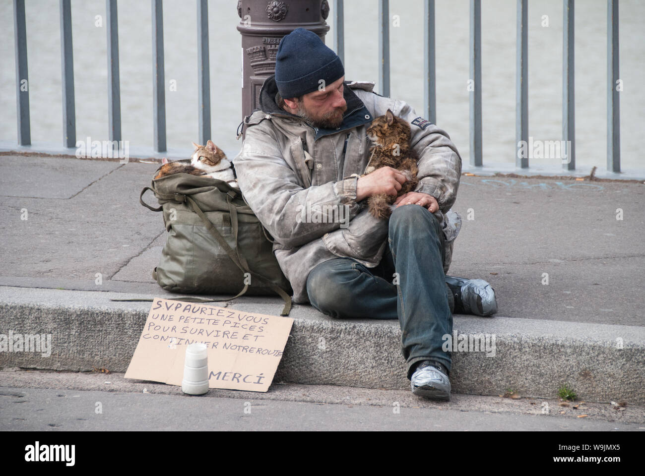 Parigi, Francia - 20 Aprile 2008: senzatetto e i suoi gatti seduti sul cordolo del Pont Saint Louis con un segno chiedendo Si prega per qualche cambiamento di ricambio Foto Stock