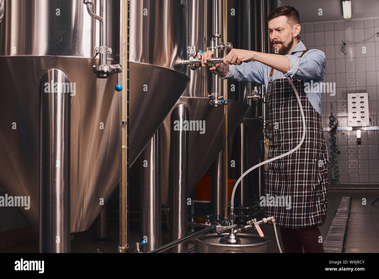 Produttore di birra miscele di tipi di birra in barile come egli tenta di effettuare ulteriori scelte flavoral. Foto Stock
