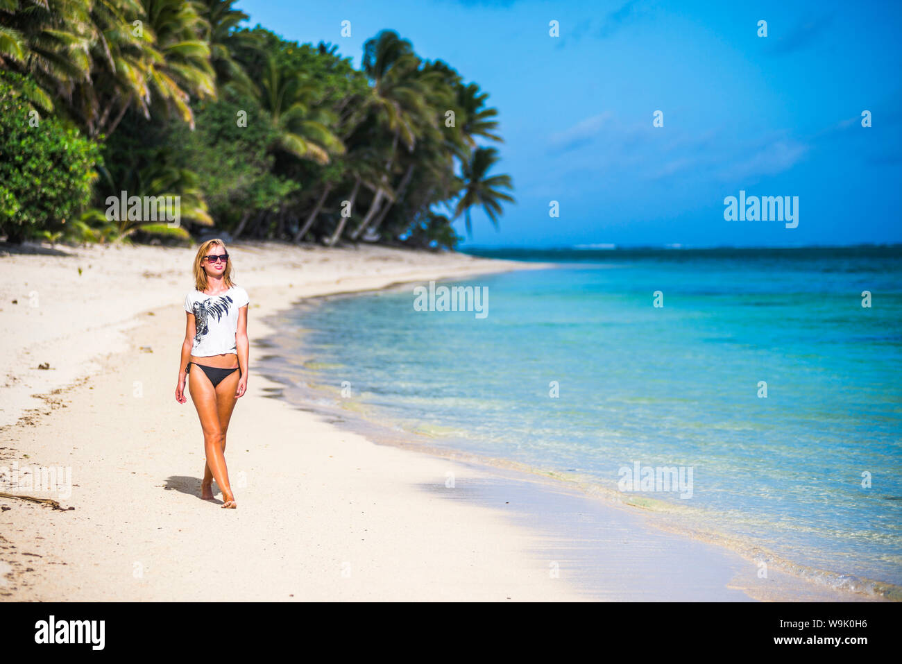 Donna che cammina lungo una spiaggia tropicale, Isola di Rarotonga Isole Cook, South Pacific Pacific Foto Stock