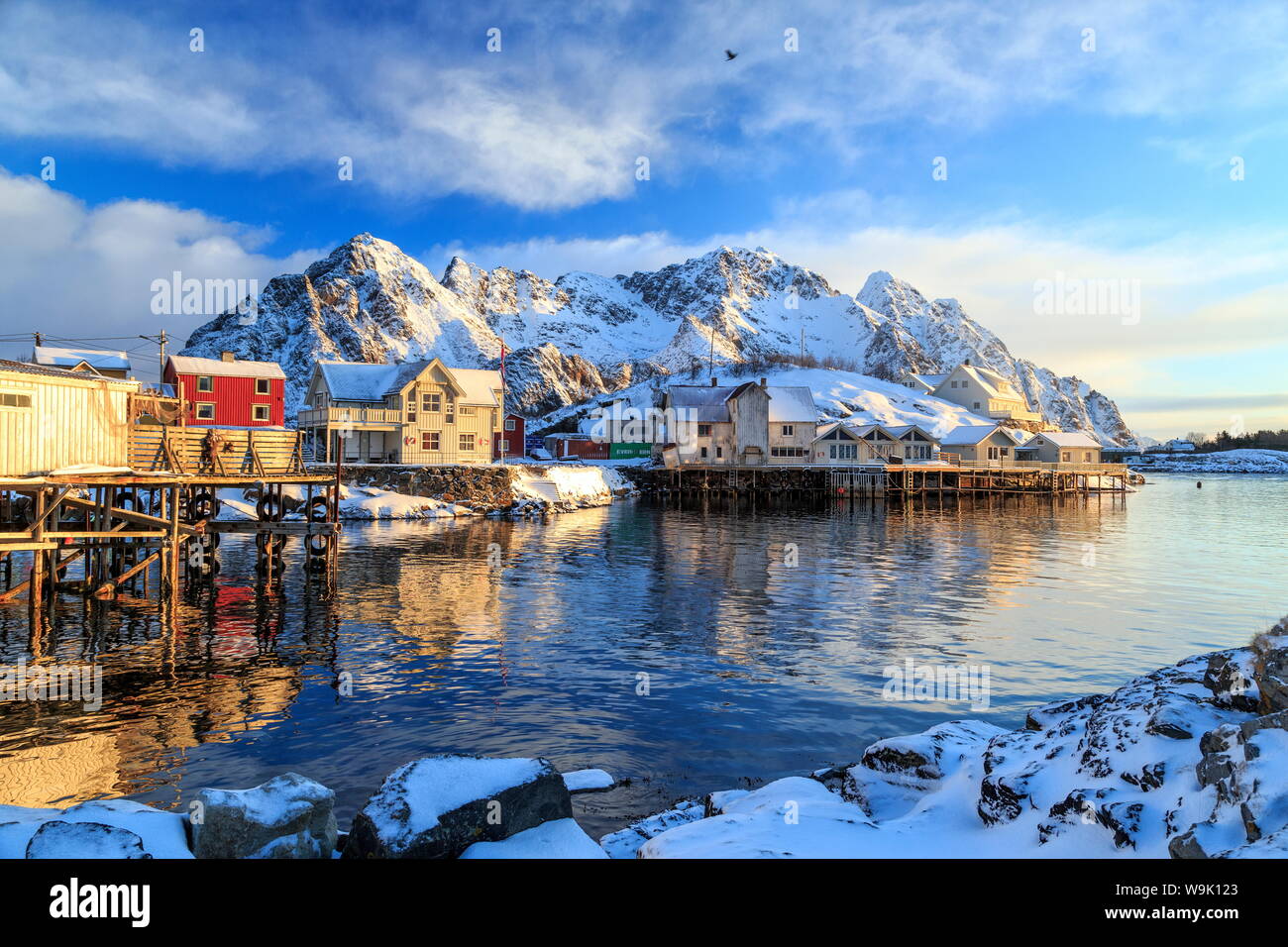 La pittura di sun le case che si affaccia sul porto di Henningsvaer nelle prime ore del mattino, Isole Lofoten artico, Norvegia, Scandinavia, Europa Foto Stock
