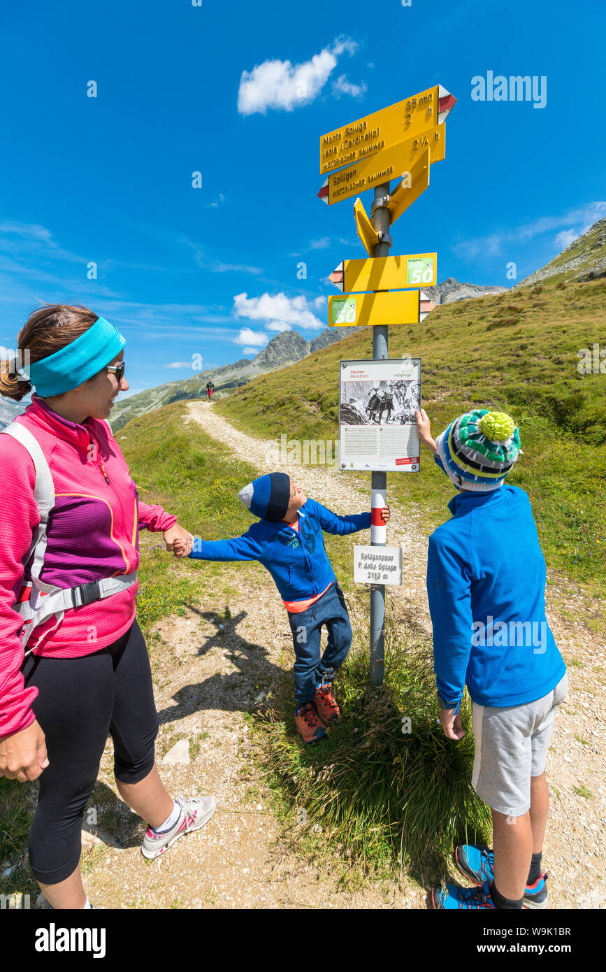 Madre e figli guardare la segnaletica dei sentieri escursionistici, Passo dello Spluga, Val Chiavenna, Valle Spluga, Lombardia, Italia, Europa Foto Stock