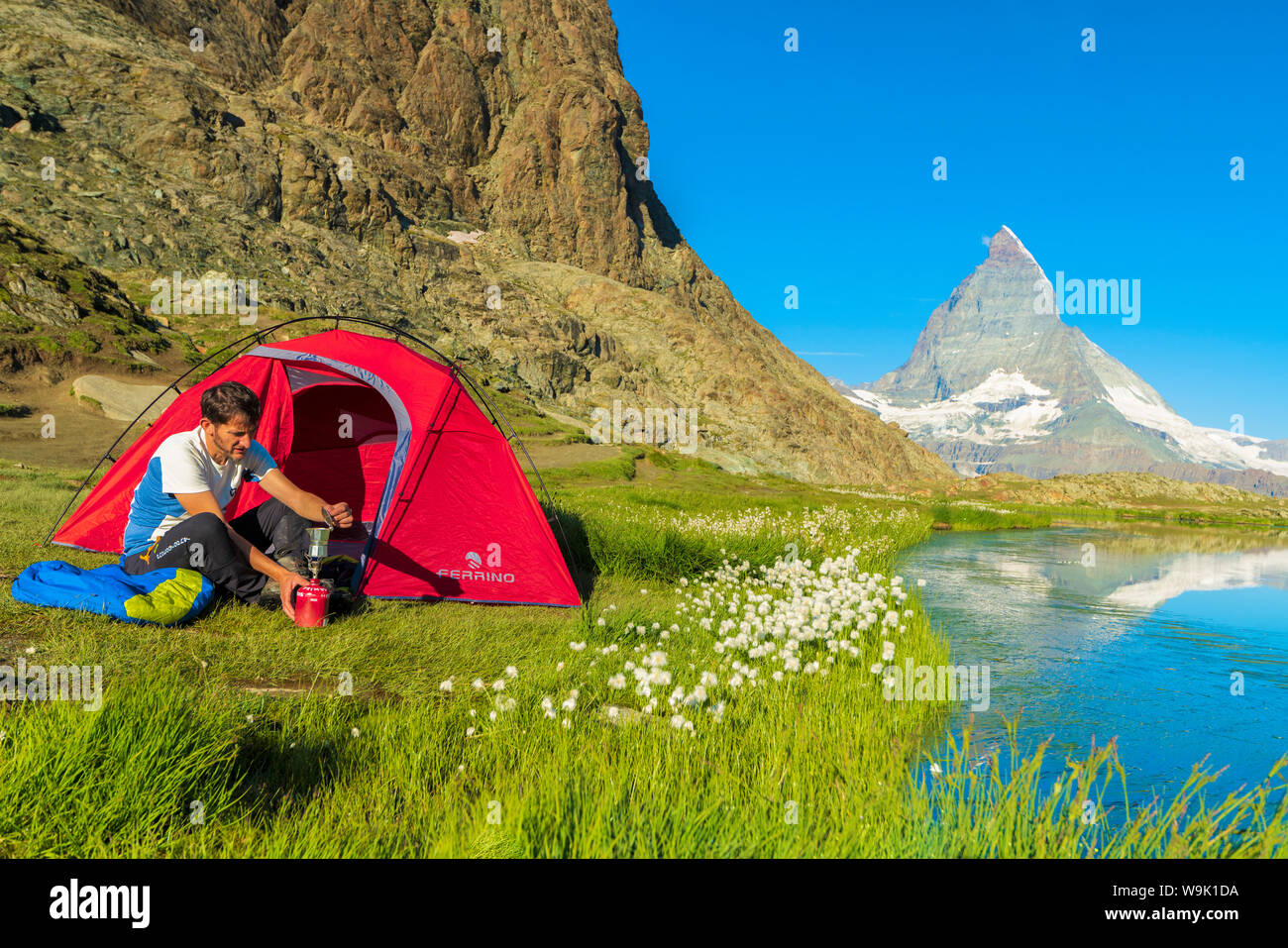 Escursionista presso il lago Riffelsee fa caffè tenda esterna affacciata sul Cervino e Zermatt, canton Vallese, alpi svizzere, Svizzera, Europa Foto Stock