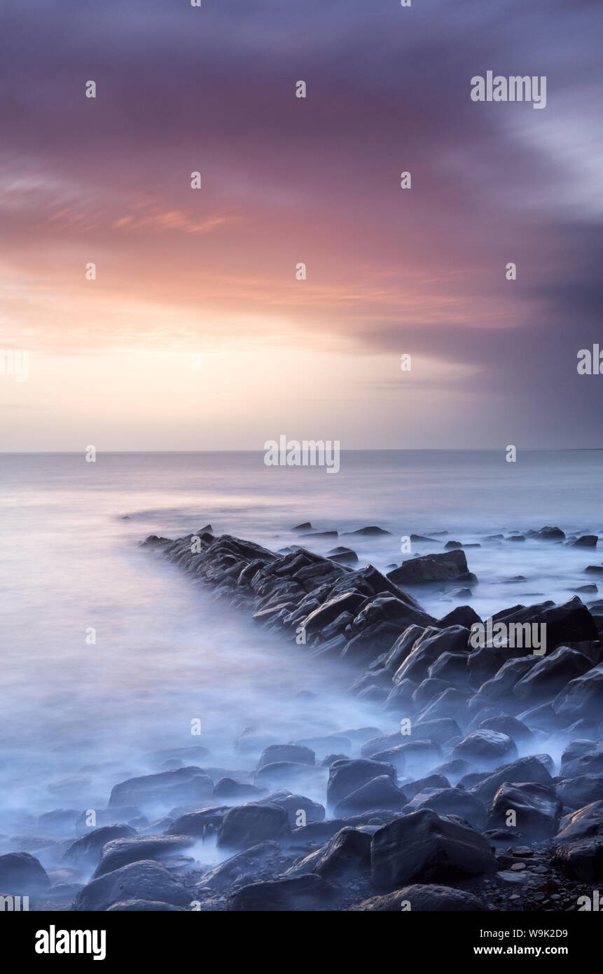 Tramonto su una tempesta del giorno guardando attraverso Kimmeridge Bay da resti di Clavell è Pier, Kimmeridge, vicino a Swanage, Dorset, England, Regno Unito Foto Stock