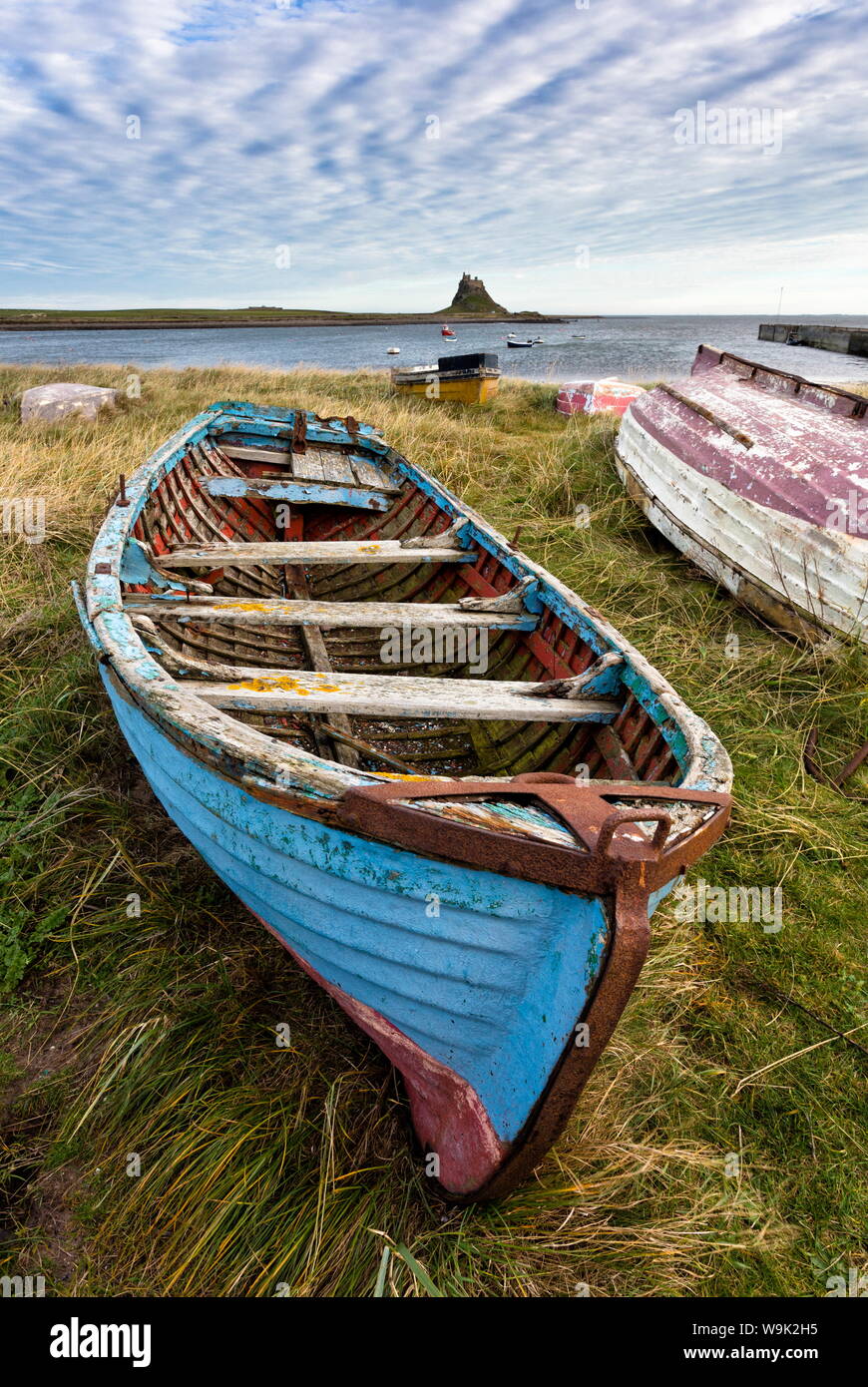 Vista in direzione di Lindisfarne Castle con un vecchio di blu e di rosso la pesca in barca in primo piano, Lindisfarne (Isola Santa), Northumberland, England, Regno Unito Foto Stock