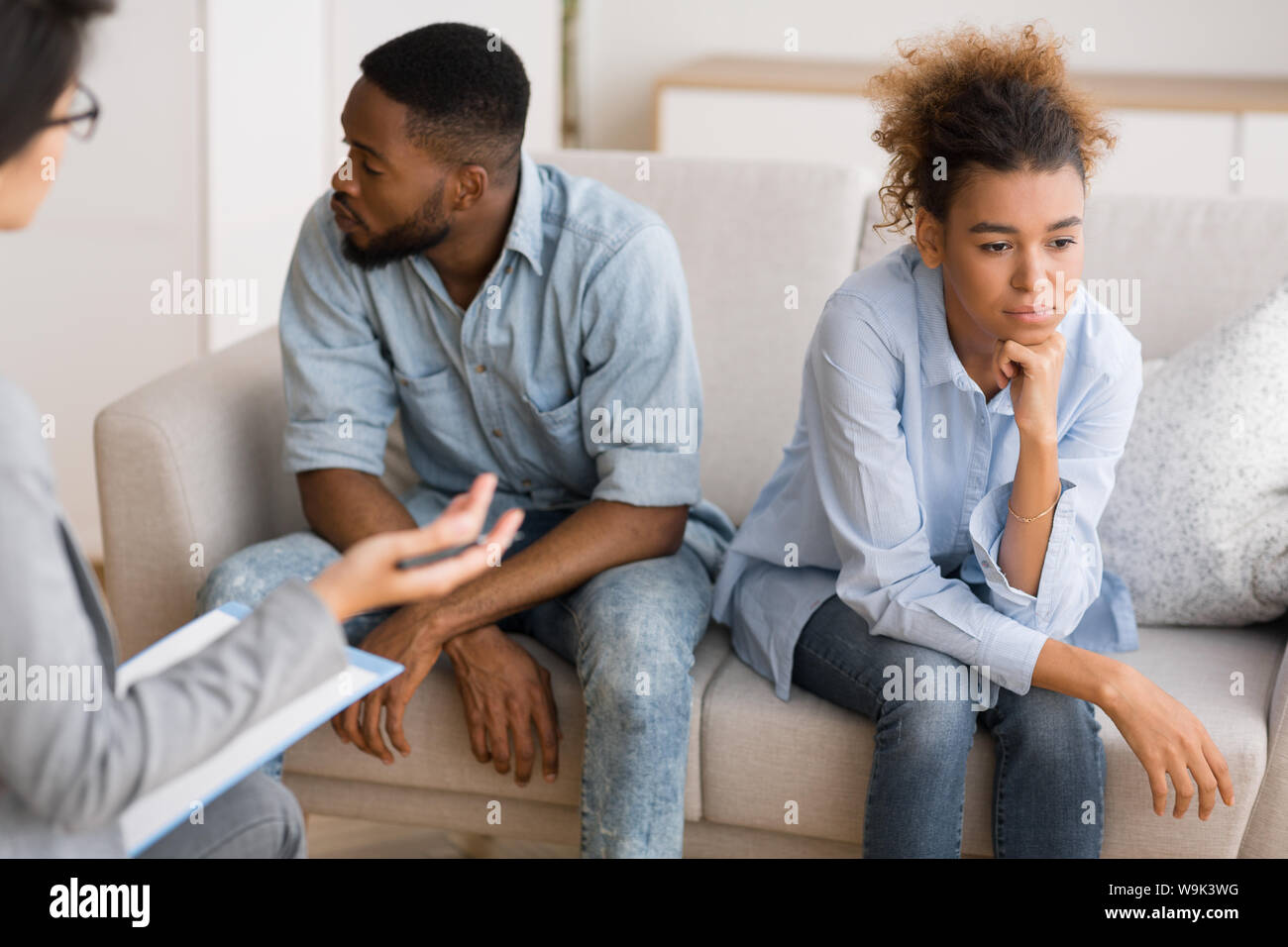 Frustrati Afro giovane evitando il contatto visivo seduti al terapeuta di Office Foto Stock
