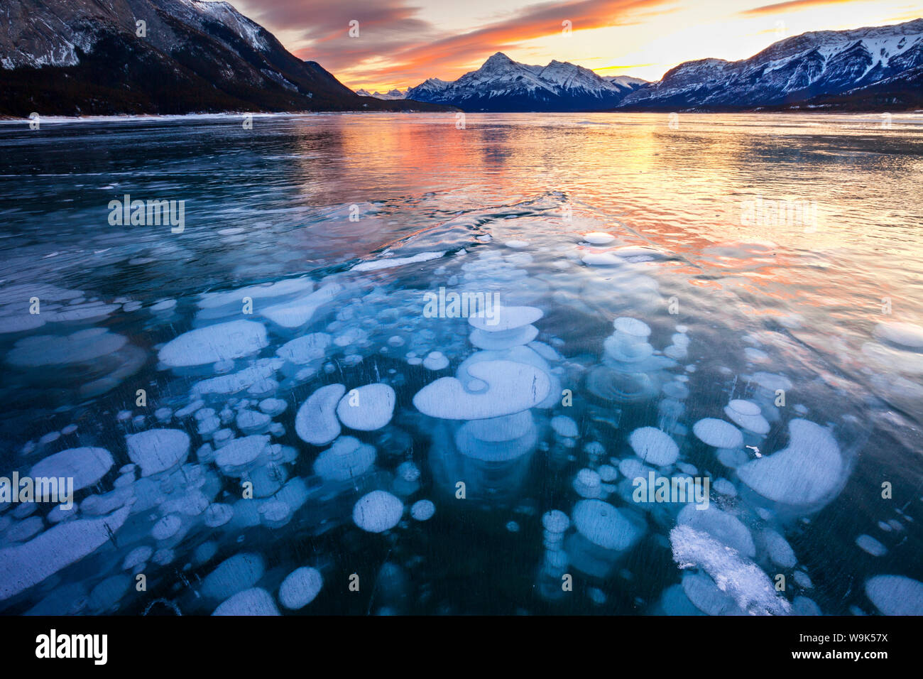 Bolle e crepe nel ghiaccio con picco di Elliot in background al tramonto, Lago di Abramo, Alberta, Canada, America del Nord Foto Stock
