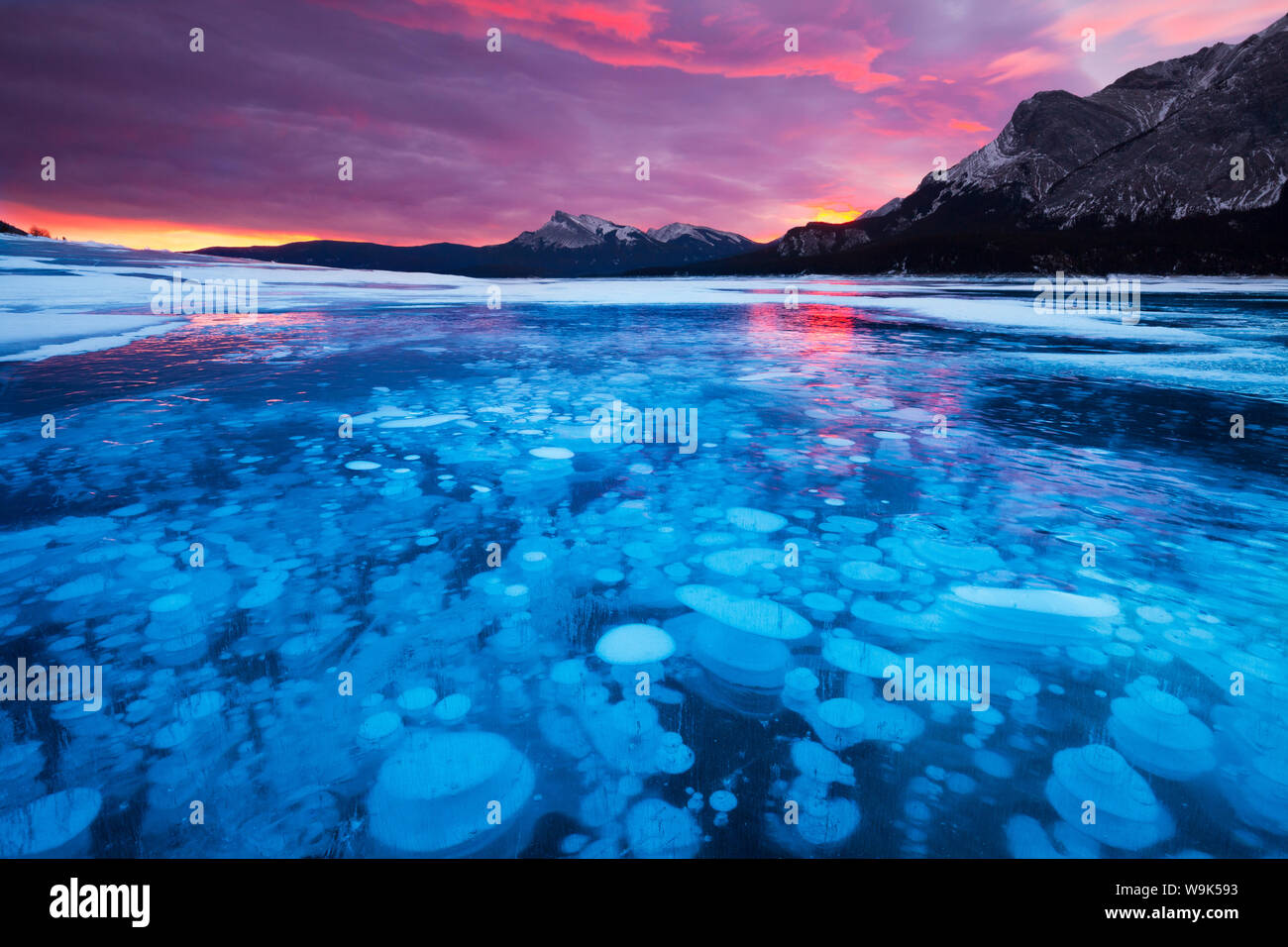 Bolle e crepe nel ghiaccio con picco di Kista in background di Sunrise, Lago di Abramo, Alberta, Canada, America del Nord Foto Stock