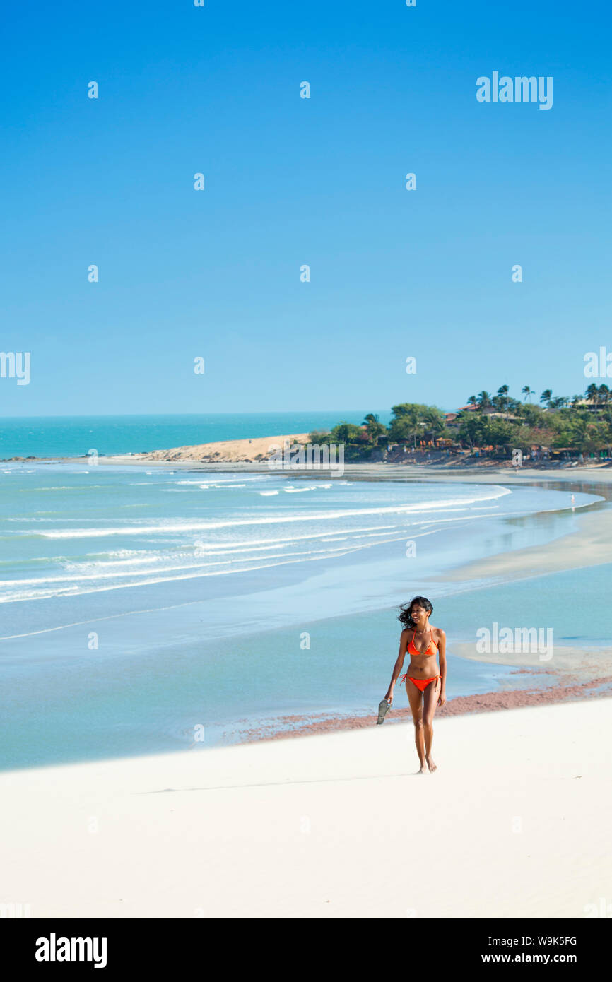 Una giovane donna a piedi lungo la spiaggia di Jericoacoara, Ceara, Brasile, Sud America Foto Stock